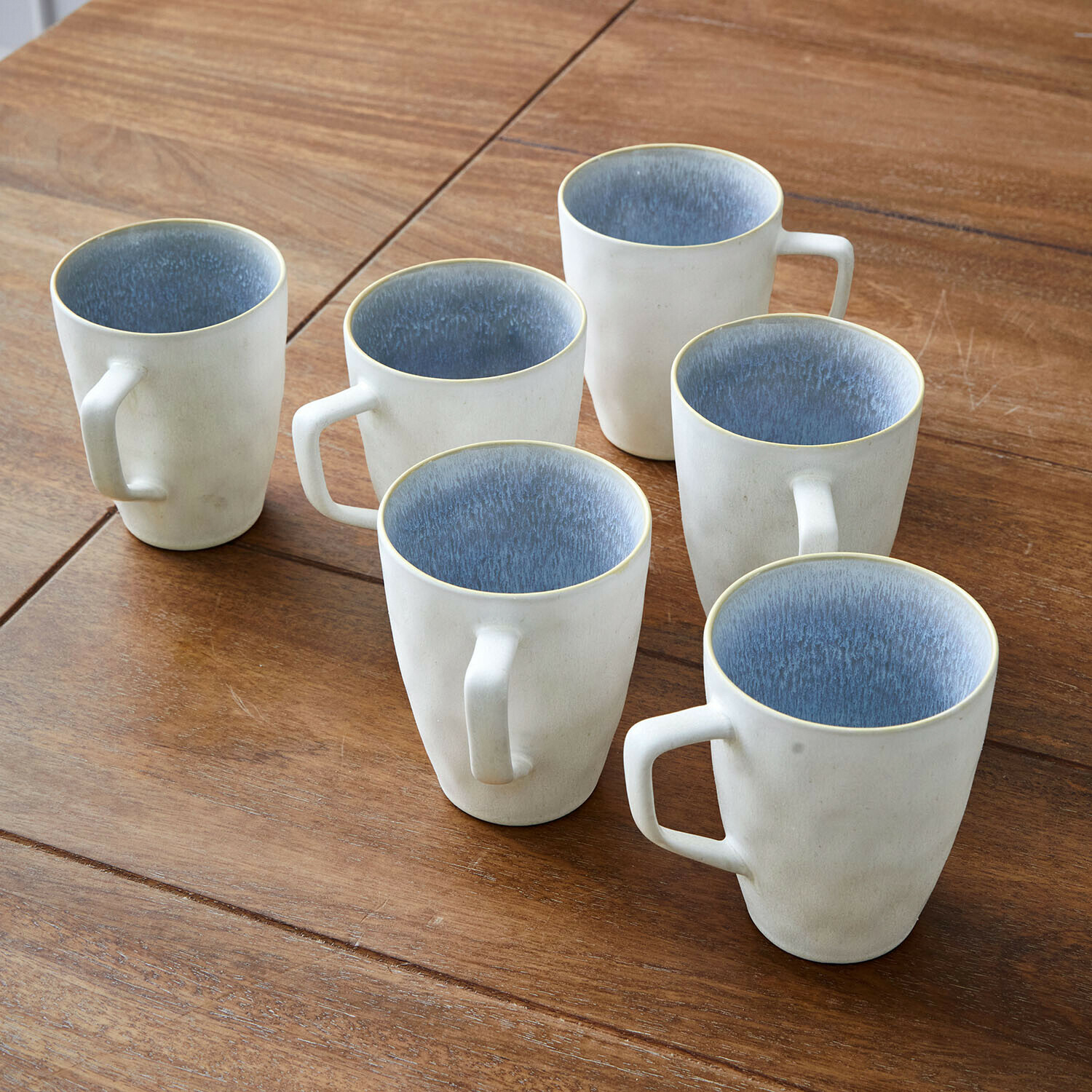 Filiżanka, zestaw 6 szt. Vionette Zestaw sześciu ceramicznych kubków w kremowym kolorze z niebieskim wnętrzem na drewnianym stole