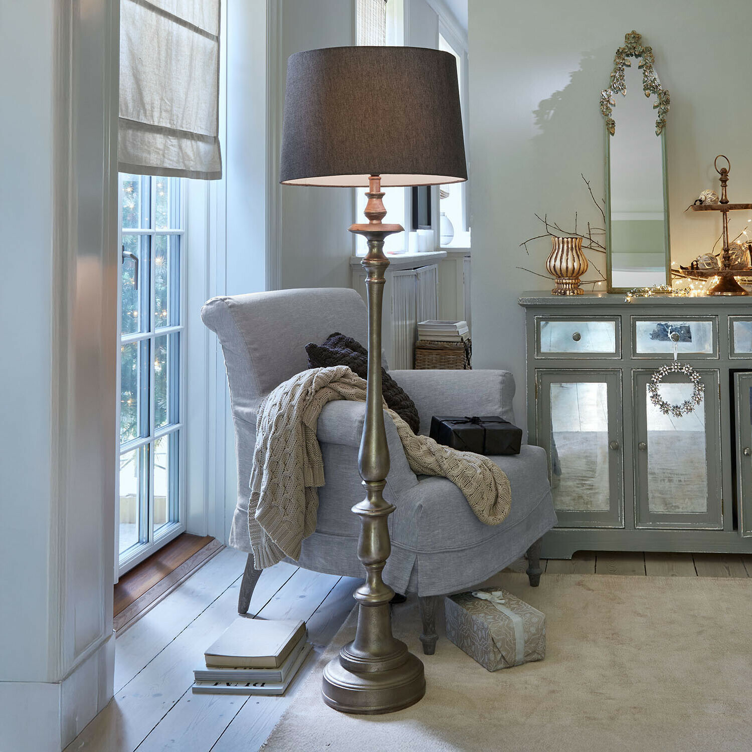 Stylowa lampa podłogowa z metalową podstawą i ciemnym abażurem w przytulnym salonie z fotelem