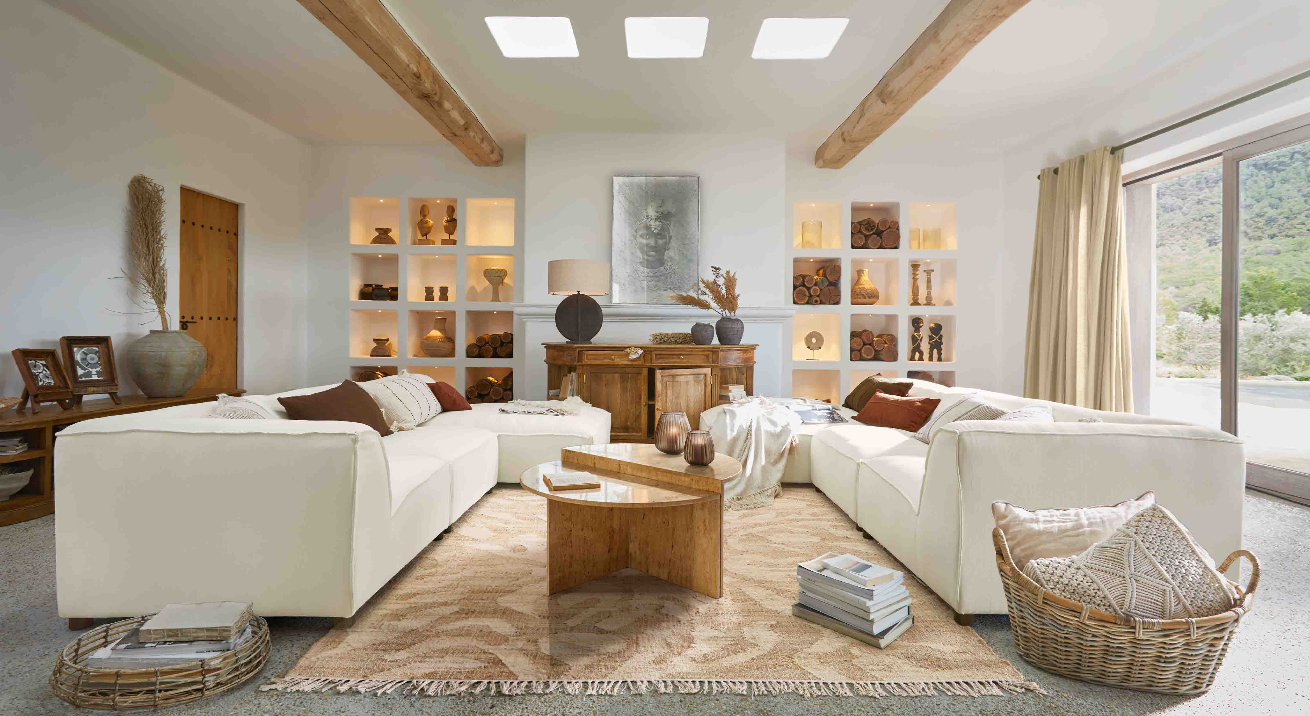 Przestronny salon z białą sofą narożną, drewnianym stolikiem i dekoracjami w naturalnych kolorach