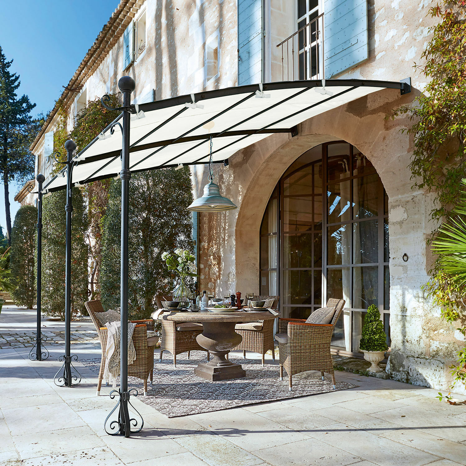 Pergola Kattles Zestaw mebli ogrodowych z wikliny pod białym daszkiem na kamiennym patio przy domu z kamienia