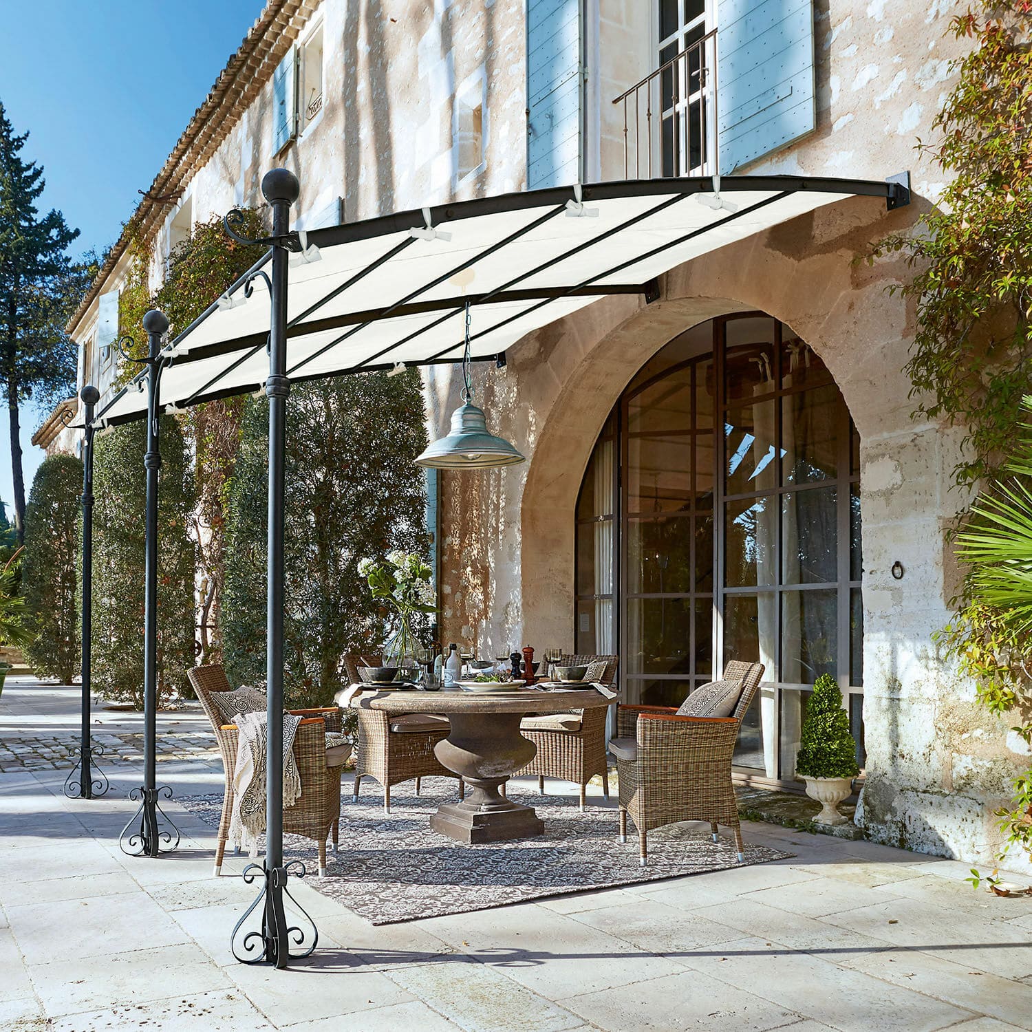 Pergola Kattles Zestaw mebli ogrodowych z wikliny pod białym daszkiem na kamiennym patio przy domu z kamienia