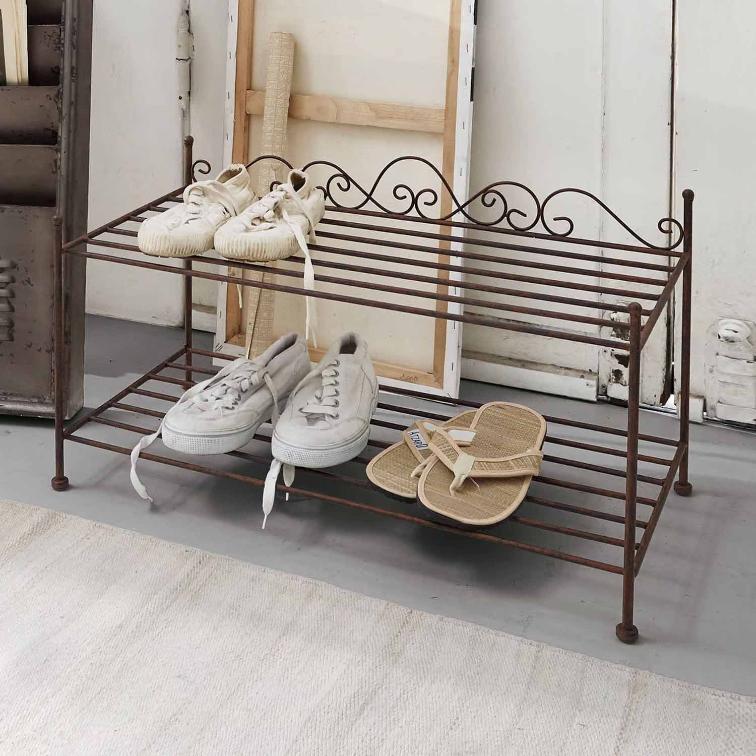 Metalowa, dwupoziomowa półka na buty w stylu vintage w kolorze rdzy z białymi i beżowymi butami