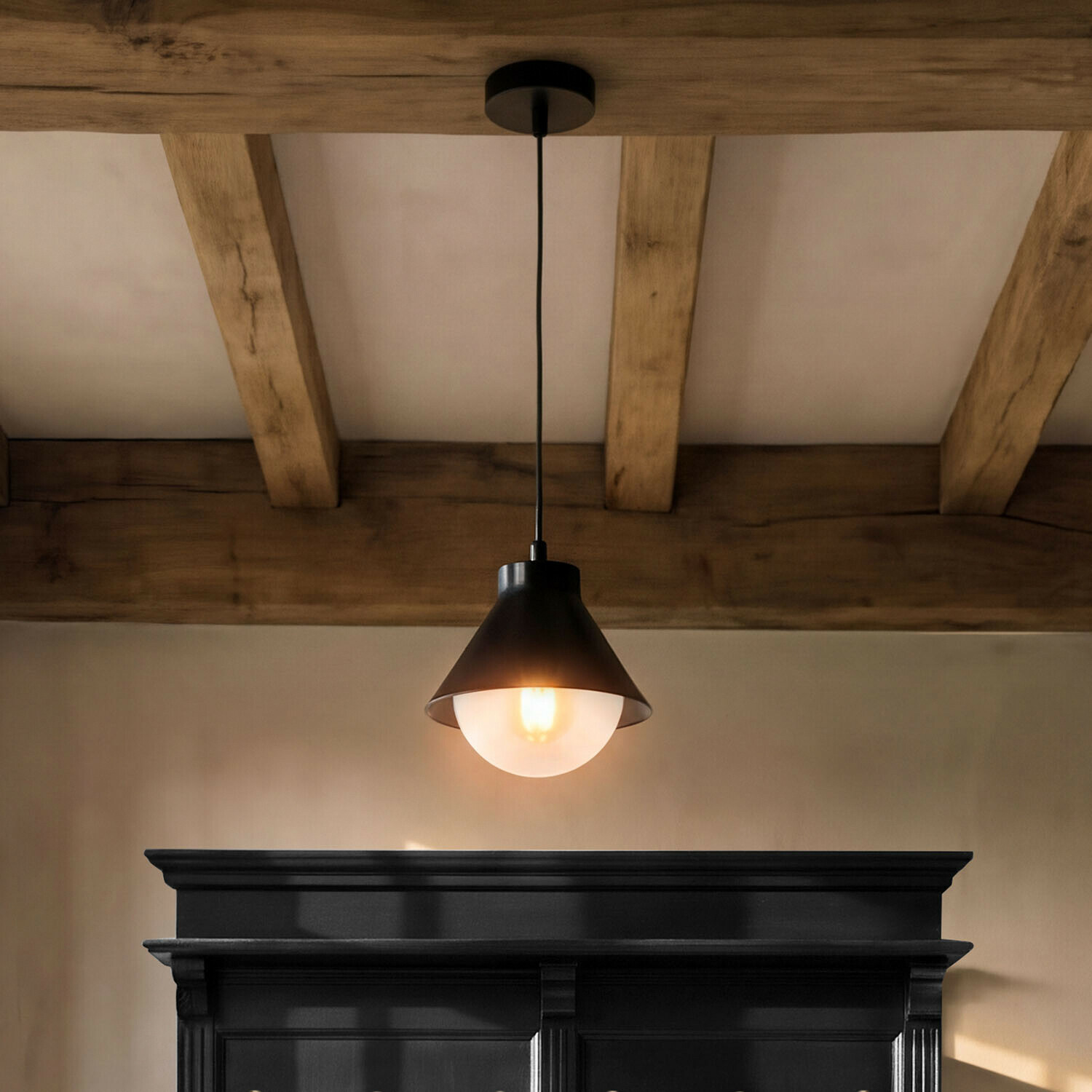 Lampa wisząca Térélune Czarna metalowa lampa wisząca z mlecznym kloszem na tle drewnianych belek sufitowych
