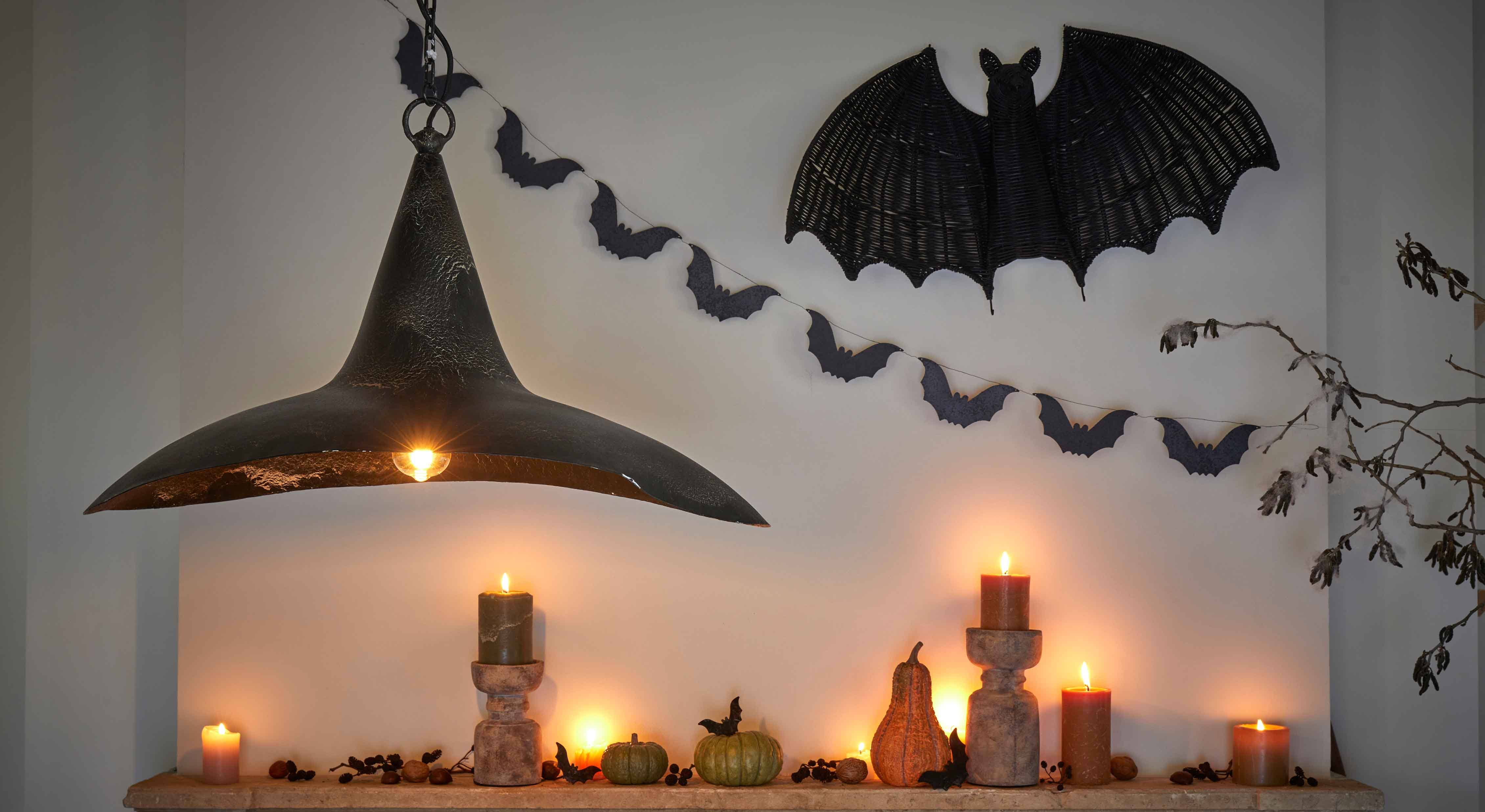 Dekoracja halloweenowa z czarnymi świecami, dyniami i lampą z czarnego metalu na ścianie z nietoperzami