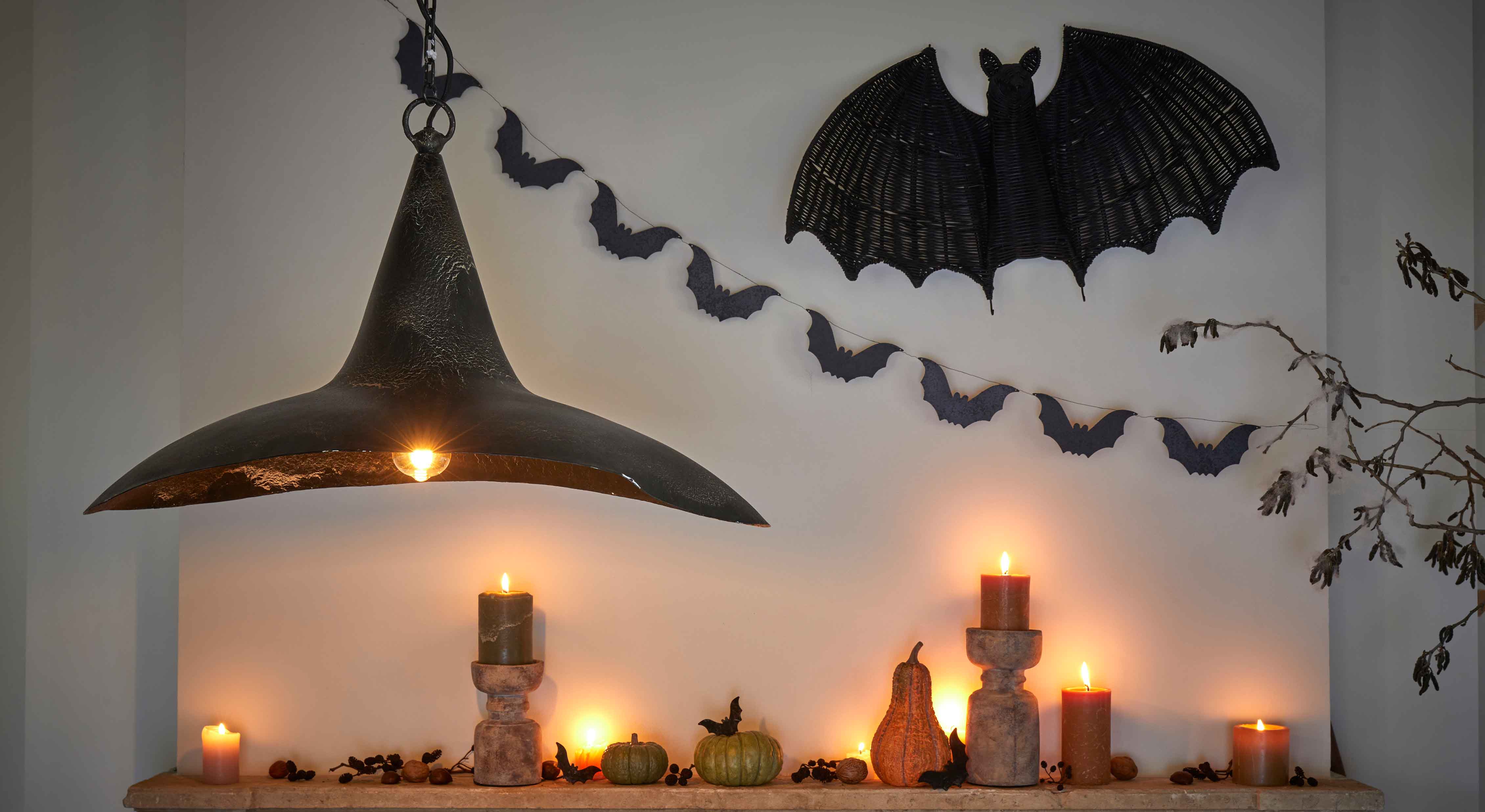 Dekoracja halloweenowa z czarnymi świecami, dyniami i lampą z czarnego metalu na ścianie z nietoperzami