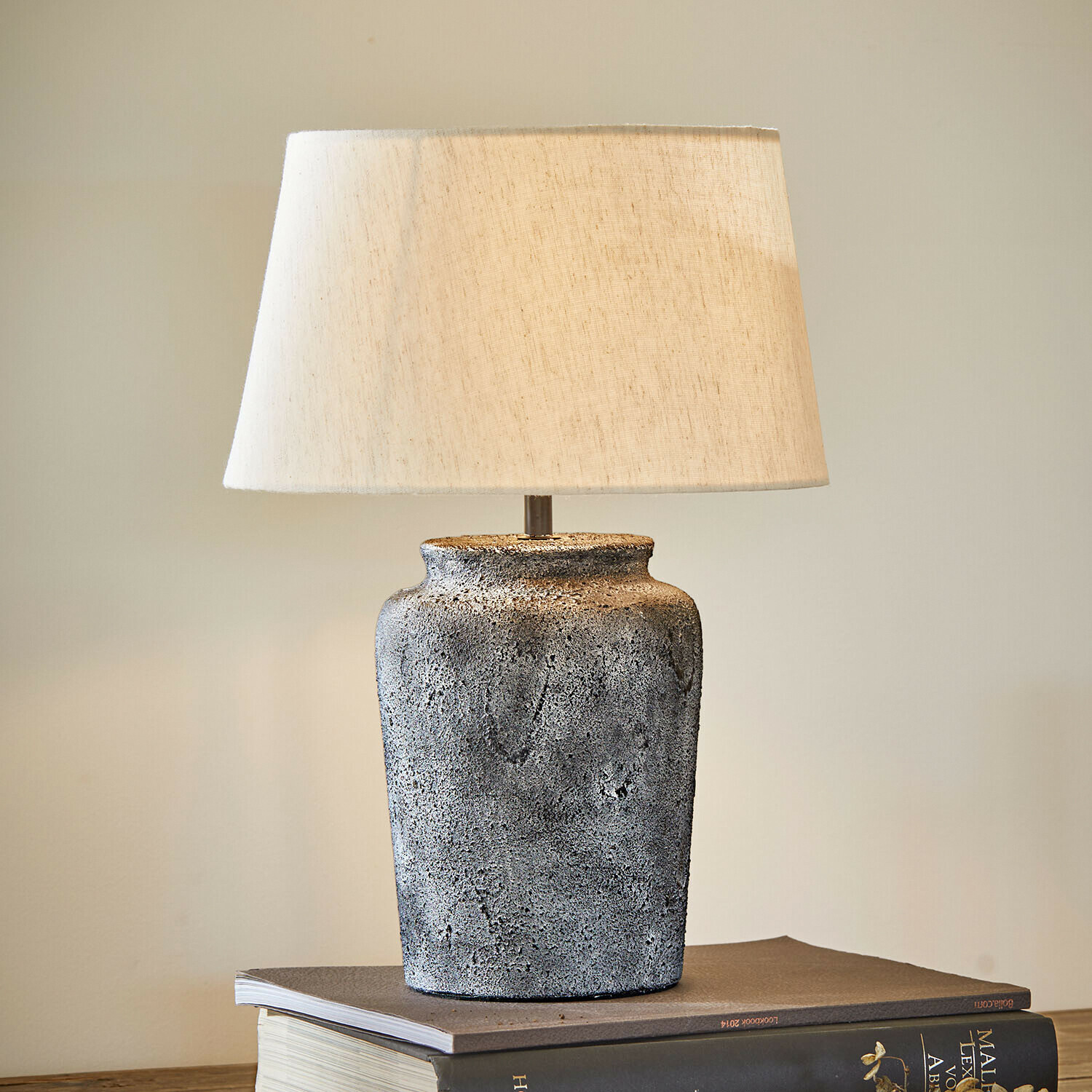 Lampa stołowa Karvienne Lampka stołowa z szarą ceramiczną podstawą i kremowym abażurem na książkach, dekoracja wnętrza