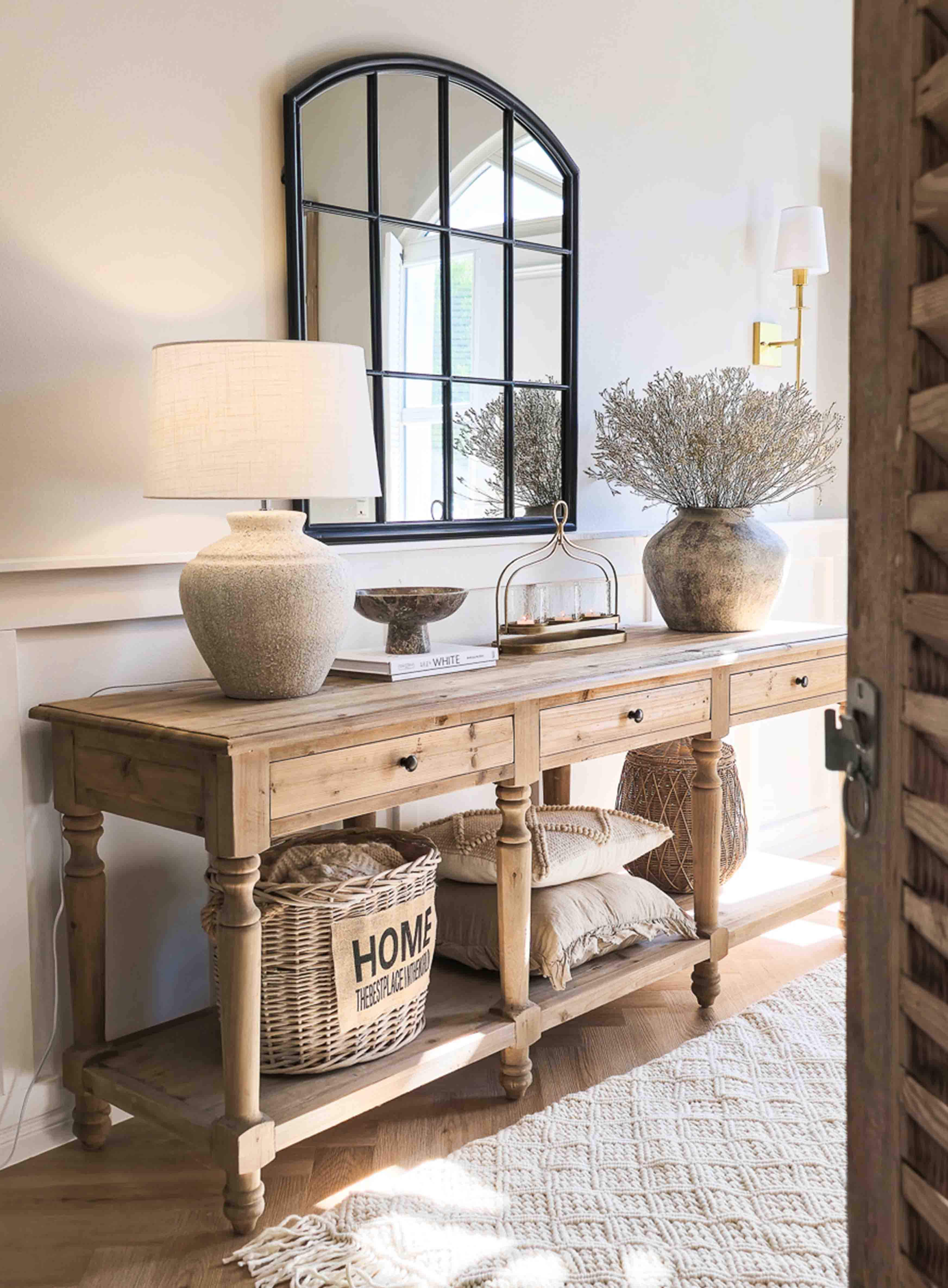 Drewniany stół konsolowy z lampą ceramiczną, lustrem z czarną ramą i dekoracją w stylu rustykalnym