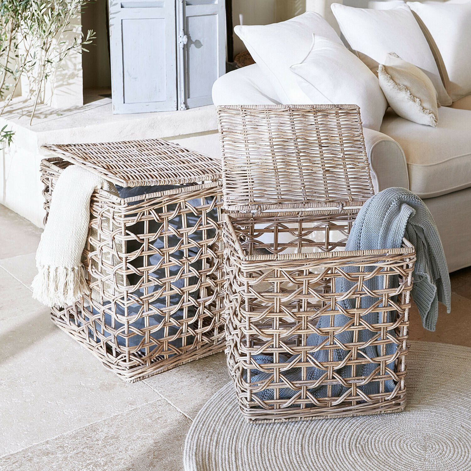 Dwa wiklinowe kosze na pranie w naturalnym kolorze z kocami, praktyczne do przechowywania w salonie