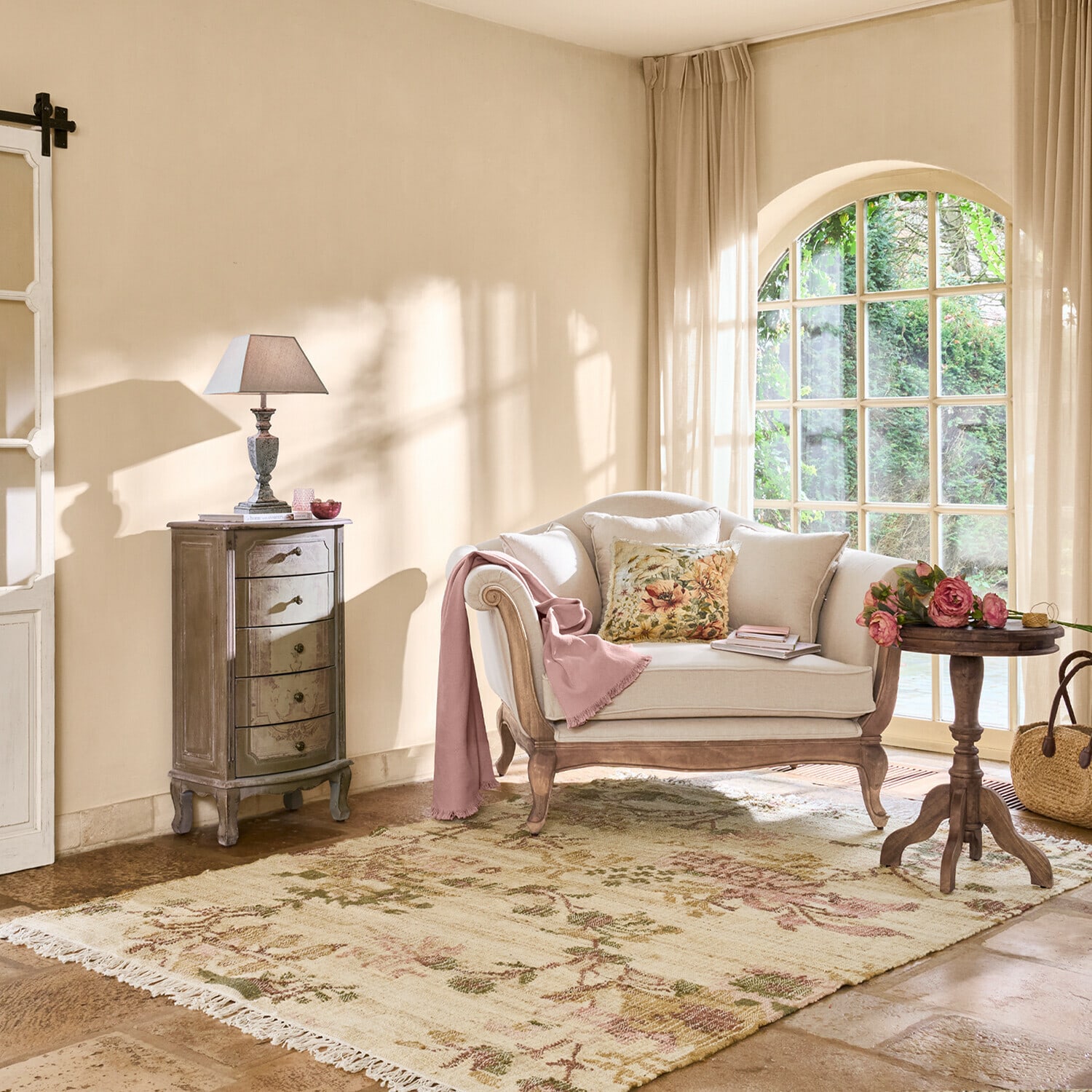 Przytulny salon z beżową sofą z drewnianą ramą, kwiatową poduszką i dywanem w kwiaty