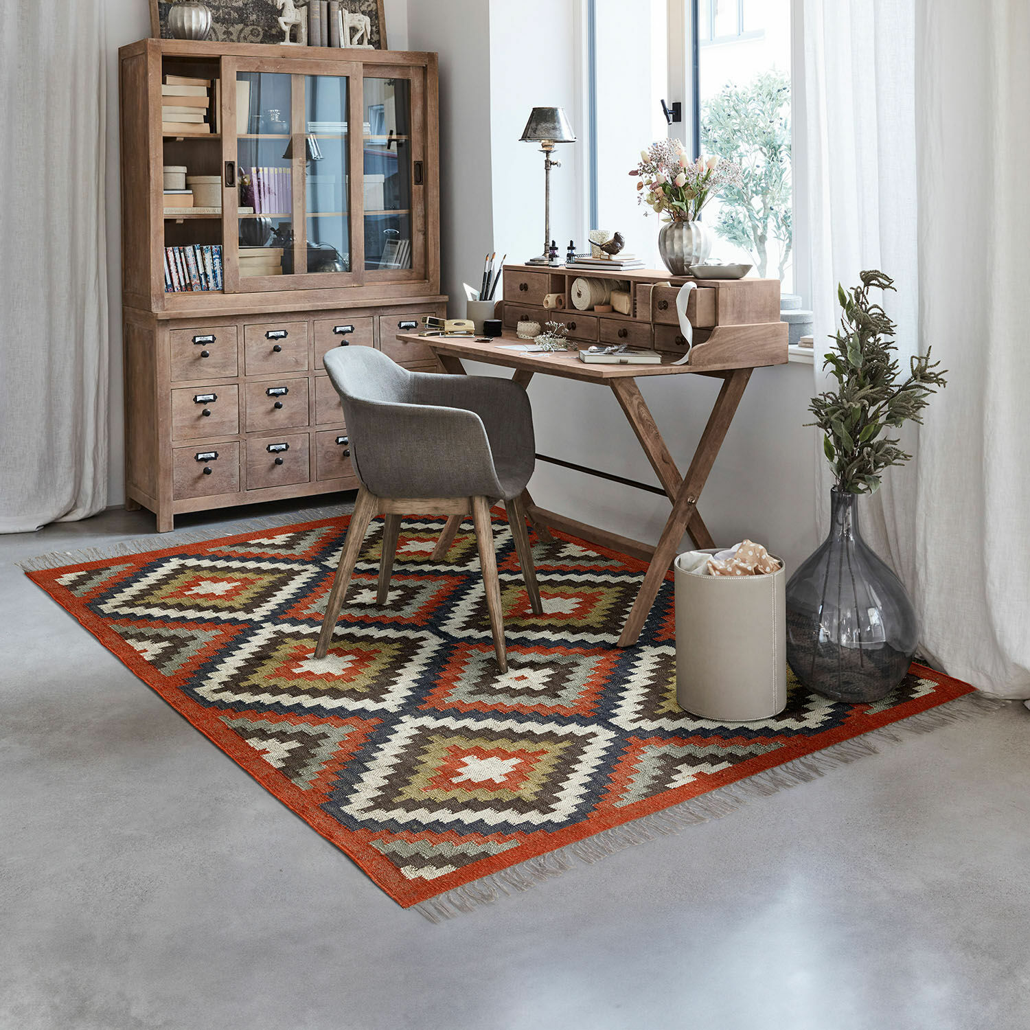 Dywan Dailies Dywan z geometrycznym wzorem w ciepłych kolorach w nowoczesnym biurze z drewnianym biurkiem i szarą tapicerką