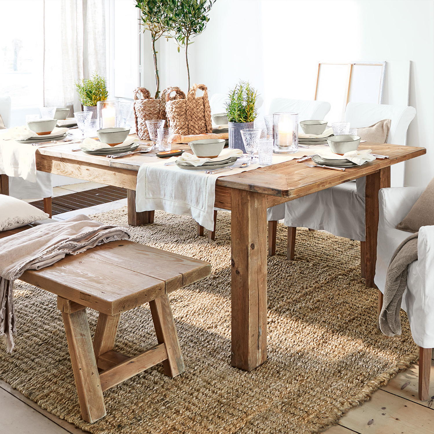 Rustykalny drewniany stół i ławka na naturalnym dywanie z dekoracjami stołu i białymi krzesłami