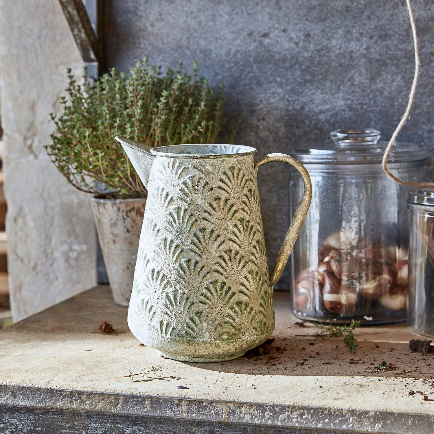 Metalowy dzbanek z zielonym wzorem i patyną na blacie, dekoracja ogrodowa i do domu