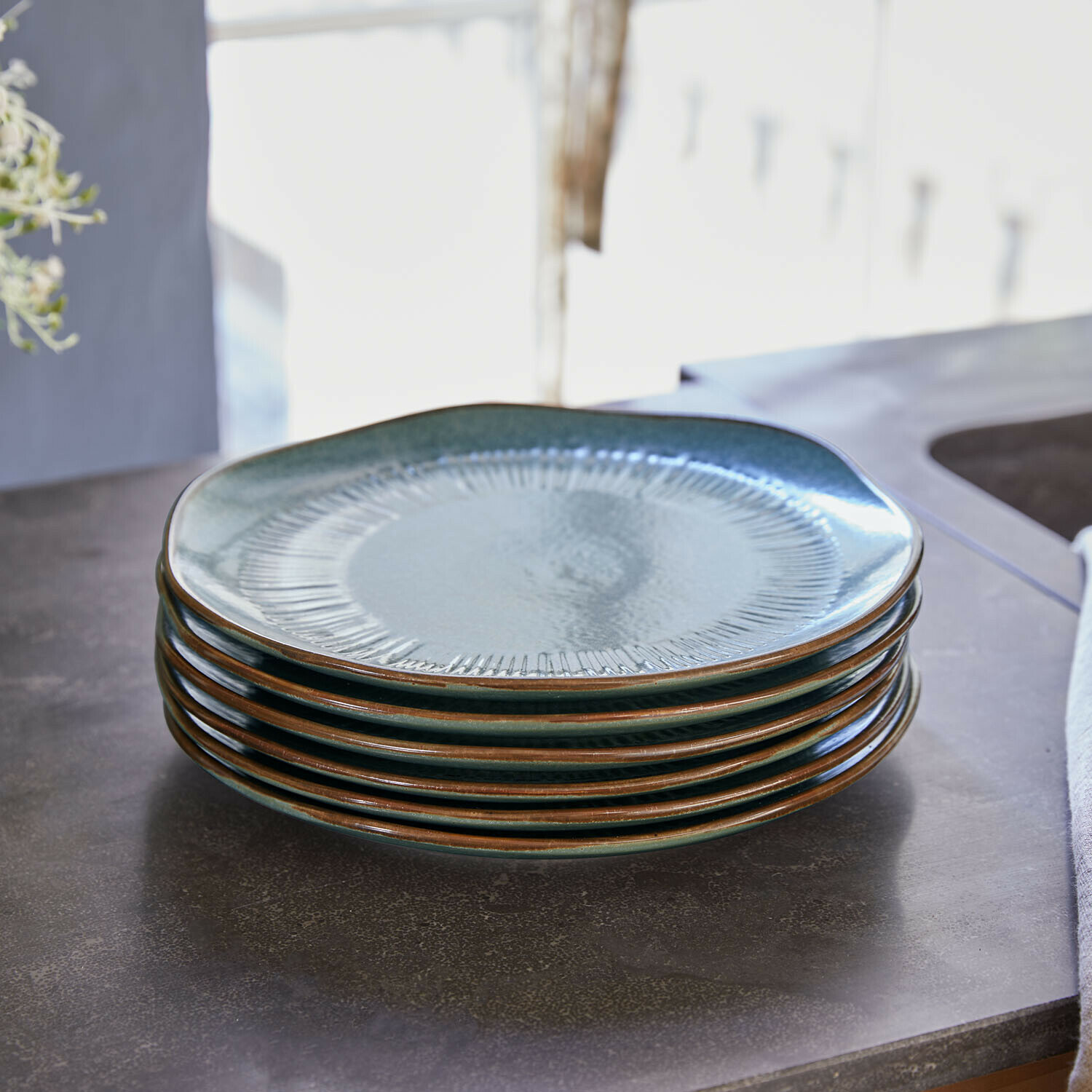 Zestaw 6 talerzy deserowych Périers Zestaw sześciu ceramicznych talerzy w zielonym kolorze z brązową krawędzią na stole kuchennym
