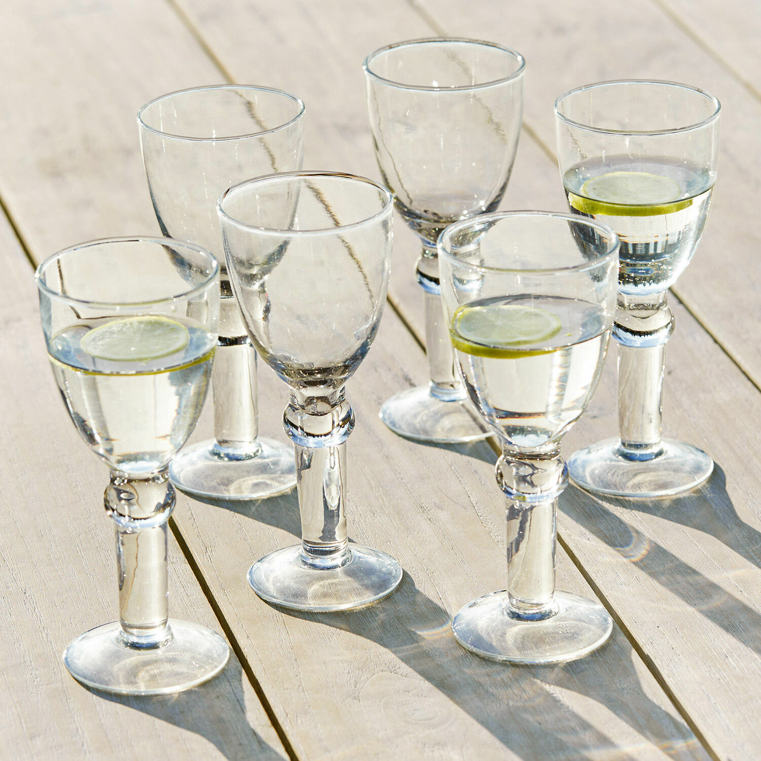 Kieliszek do wina, zestaw 6 szt. Devon Zestaw sześciu przezroczystych szklanek z wodą i plasterkami cytryny na drewnianym stole