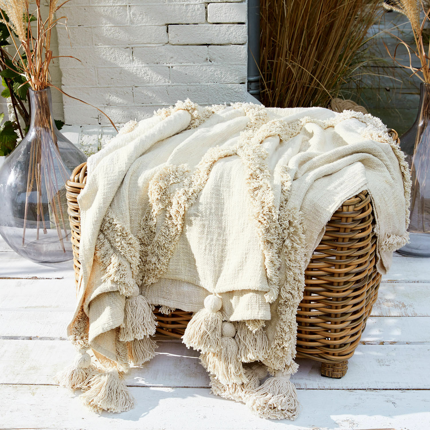 Pled Linares Kremowy bawełniany koc z frędzlami na wiklinowym koszu, dekoracja wnętrz i komfort