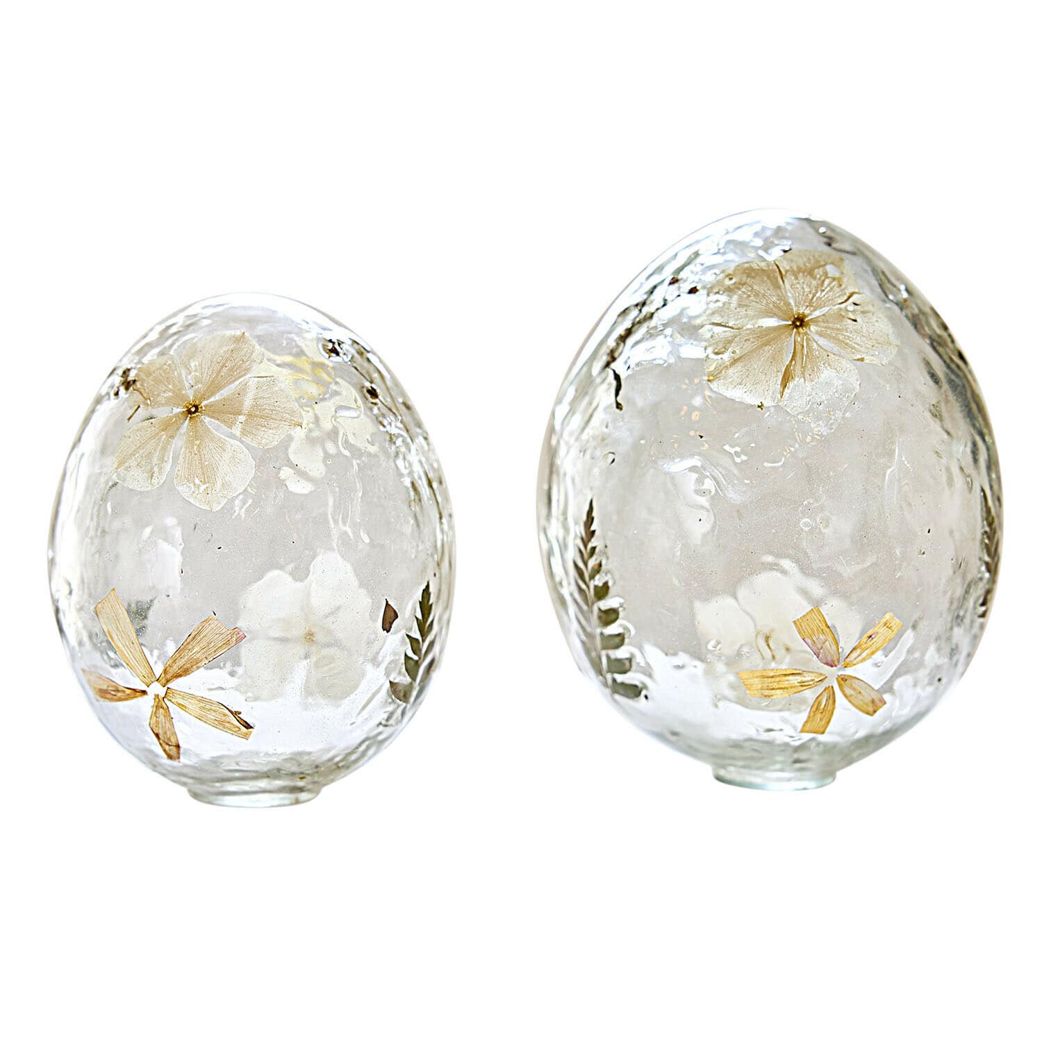 Dwa przezroczyste szklane jajka z zatopionymi suszonymi kwiatami i liśćmi, dekoracja wiosenna