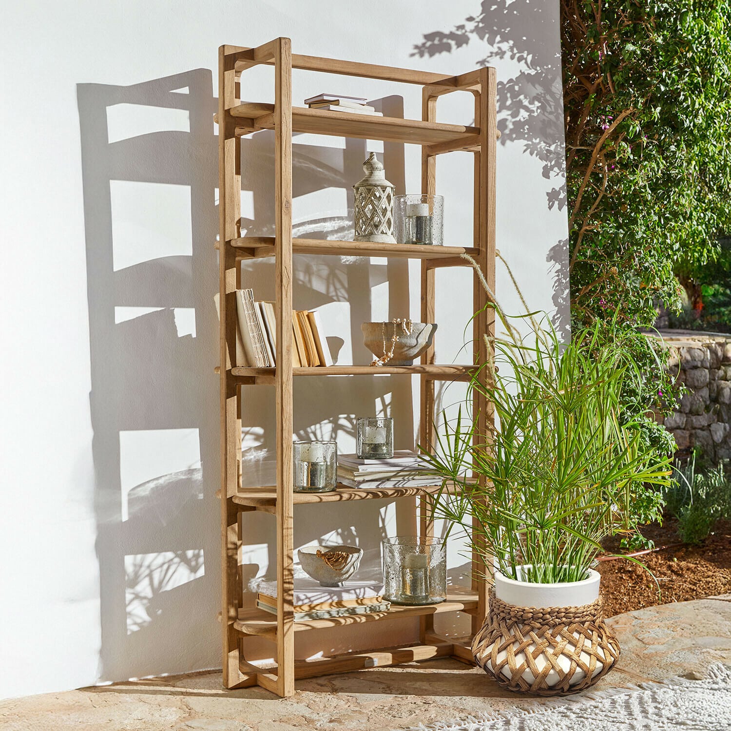 Drewniany regał z naturalnego drewna z dekoracjami i rośliną w doniczce na zewnątrz