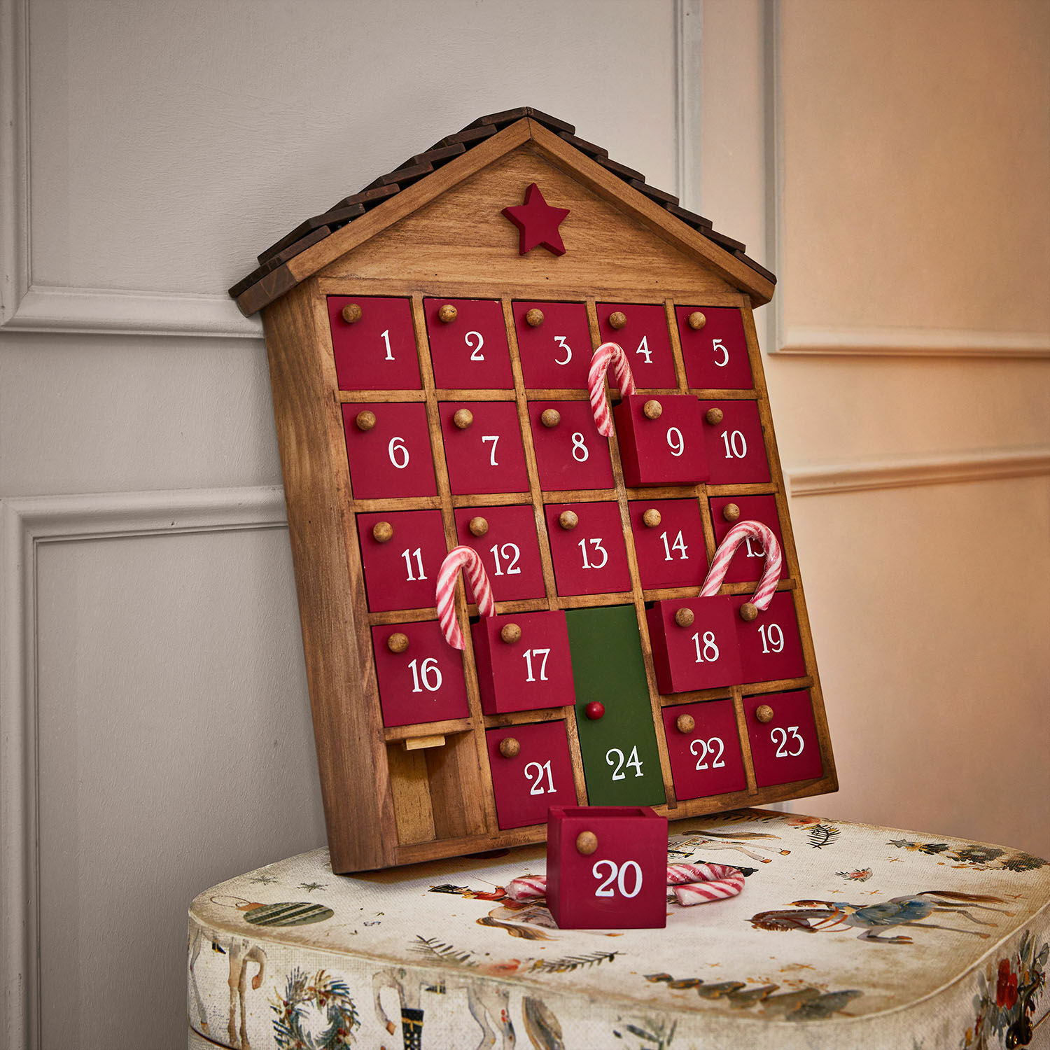 Kalendarz adwentowy Zanari Drewniany kalendarz adwentowy w kształcie domu z czerwonymi drzwiczkami i zielonym numerem 24, dekoracja świąteczna