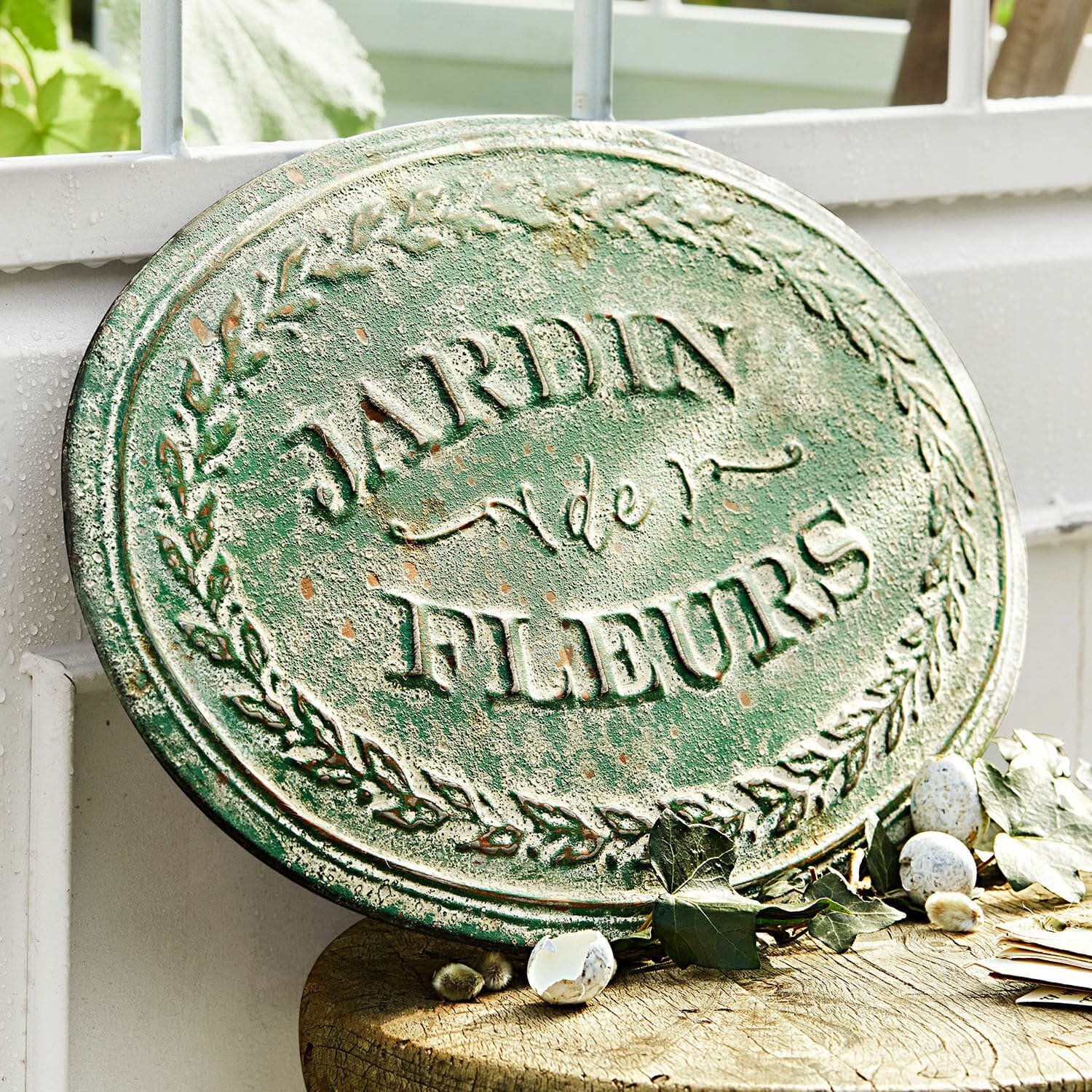 Tablica dekoracyjna Jardin de Fleurs Owalna zielona metalowa tablica ogrodowa z napisem Jardin de Fleurs i dekoracją liści
