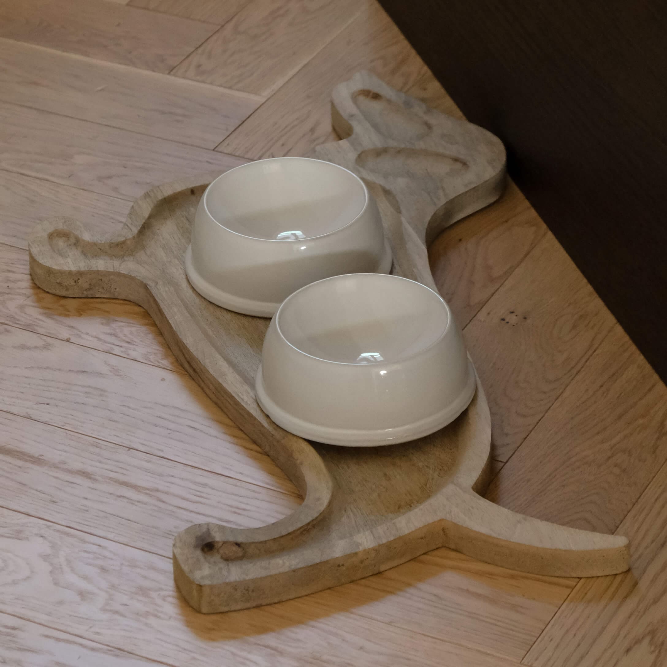 Drewniana podstawka w kształcie kota z dwoma kremowymi ceramicznymi miskami dla zwierząt