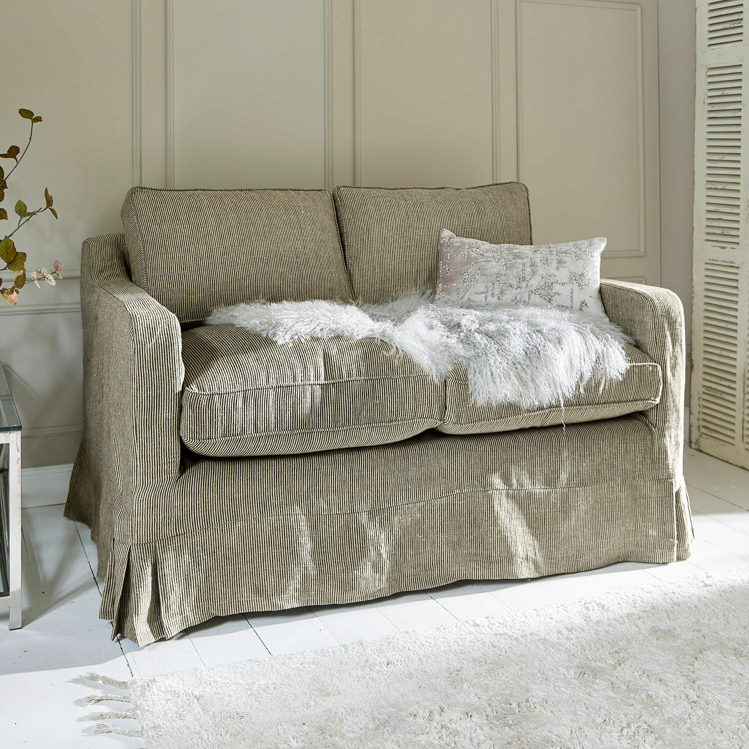 Sofa Briarcliff Dwumiejscowa sofa w beżowym prążkowanym materiale z białym futrzanym kocem i poduszką dekoracyjną