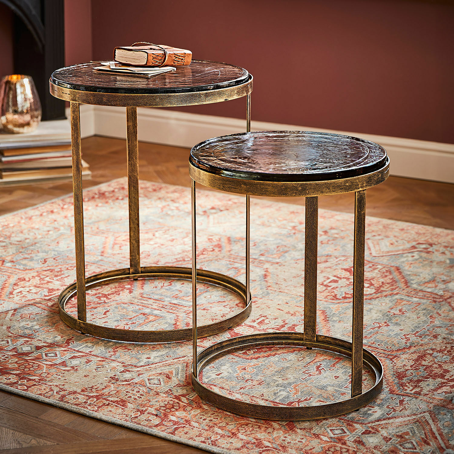 Zestaw dwóch okrągłych stolików bocznych z metalową ramą i ciemnym marmurowym blatem na dywanie