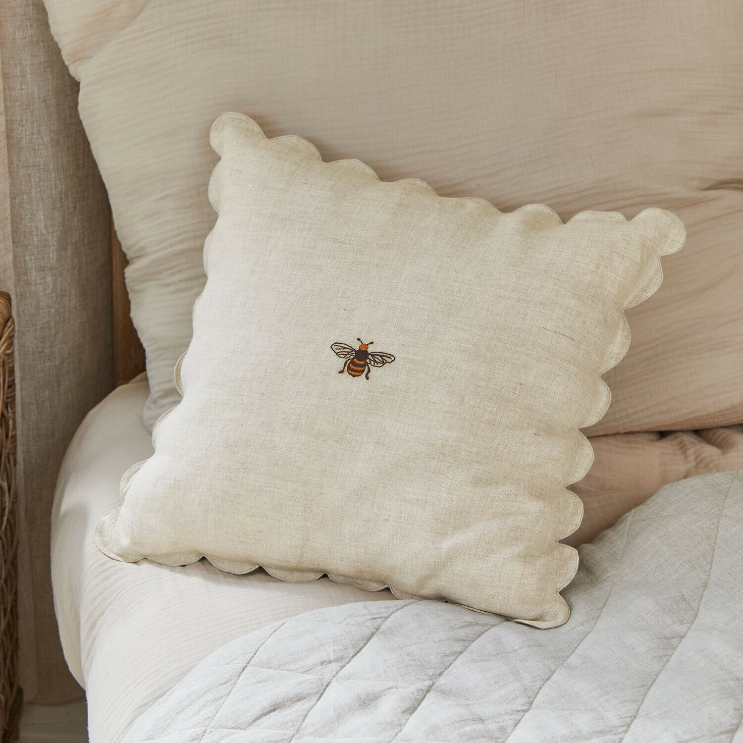 Beżowa lniana poduszka z falistym brzegiem i haftowaną pszczołą, dekoracja sypialni