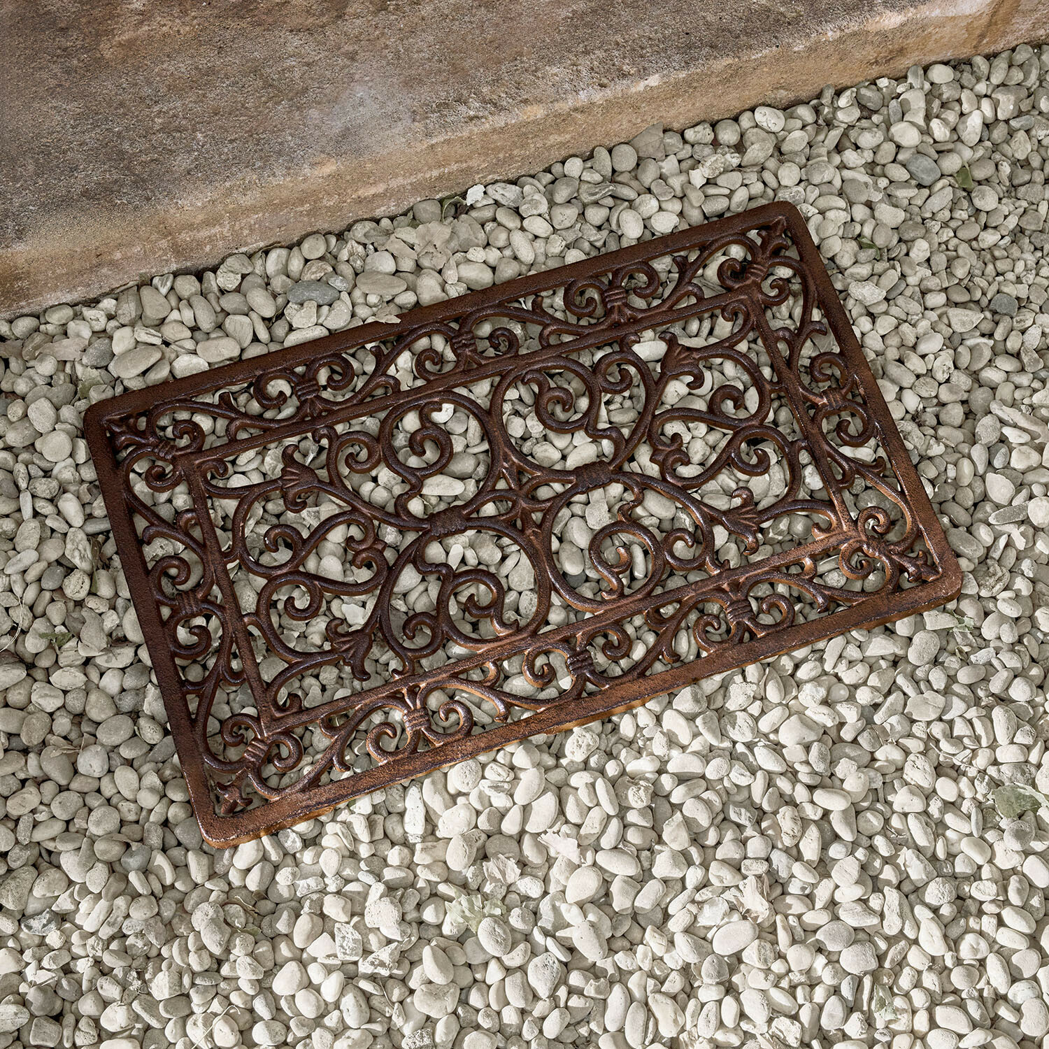 Brązowa metalowa mata z ozdobnym wzorem na białych kamieniach, mata wejściowa z żeliwa