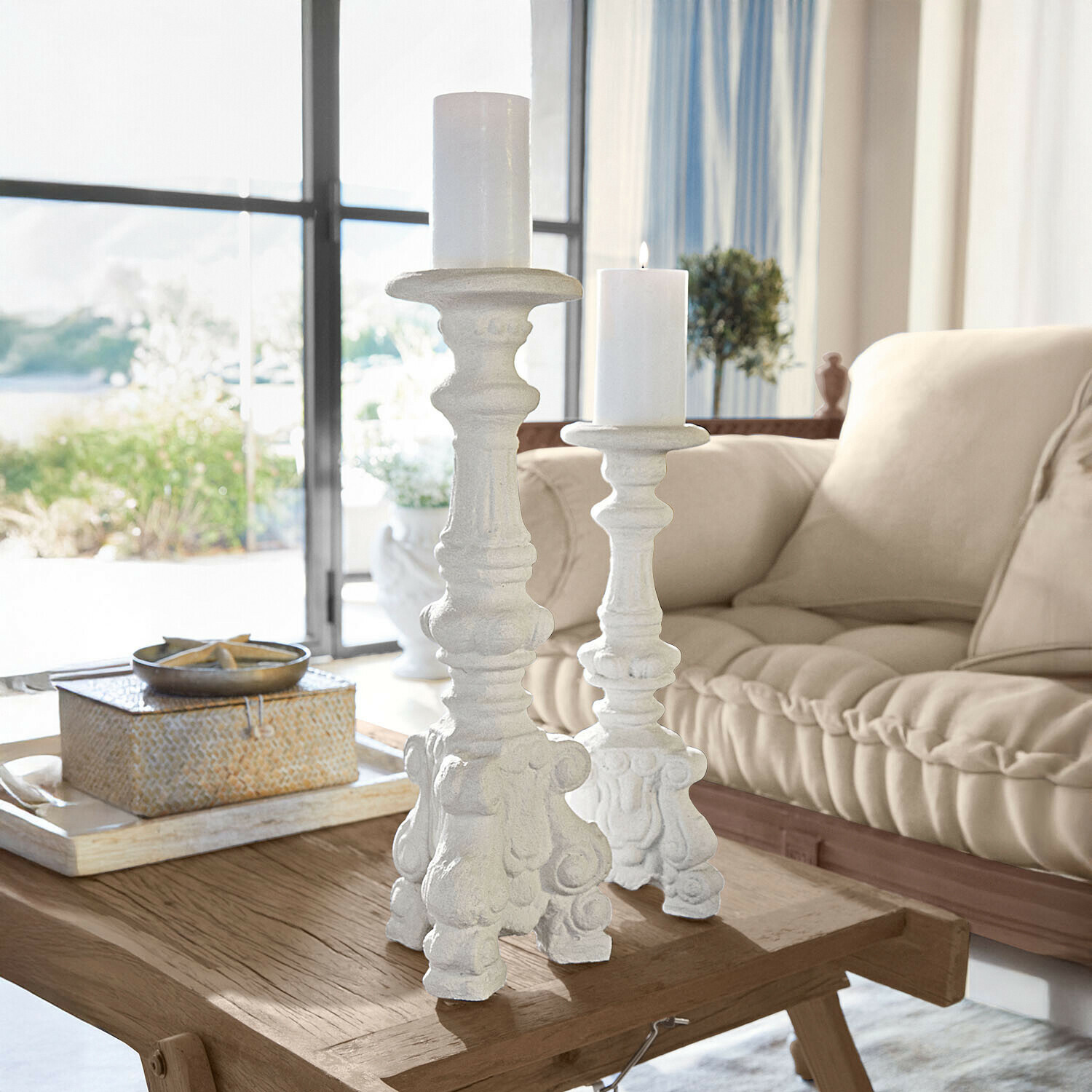 Białe dekoracyjne świeczniki z ozdobnym wzorem na drewnianym stoliku w jasnym salonie
