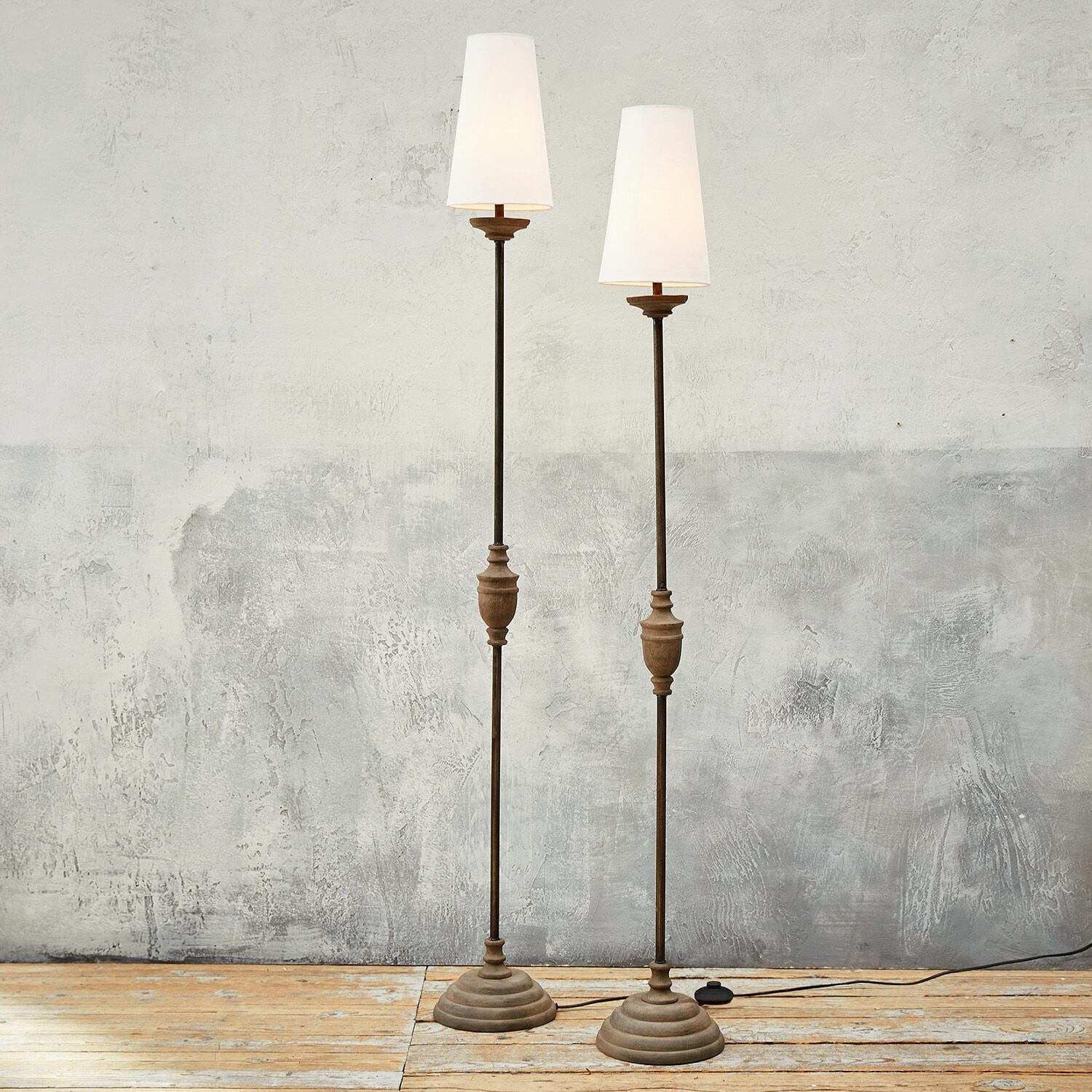 Lampa stojąca, zestaw 2 szt. Abigail Para lamp stojących z metalowymi i drewnianymi elementami oraz białymi abażurami na drewnianej podłodze