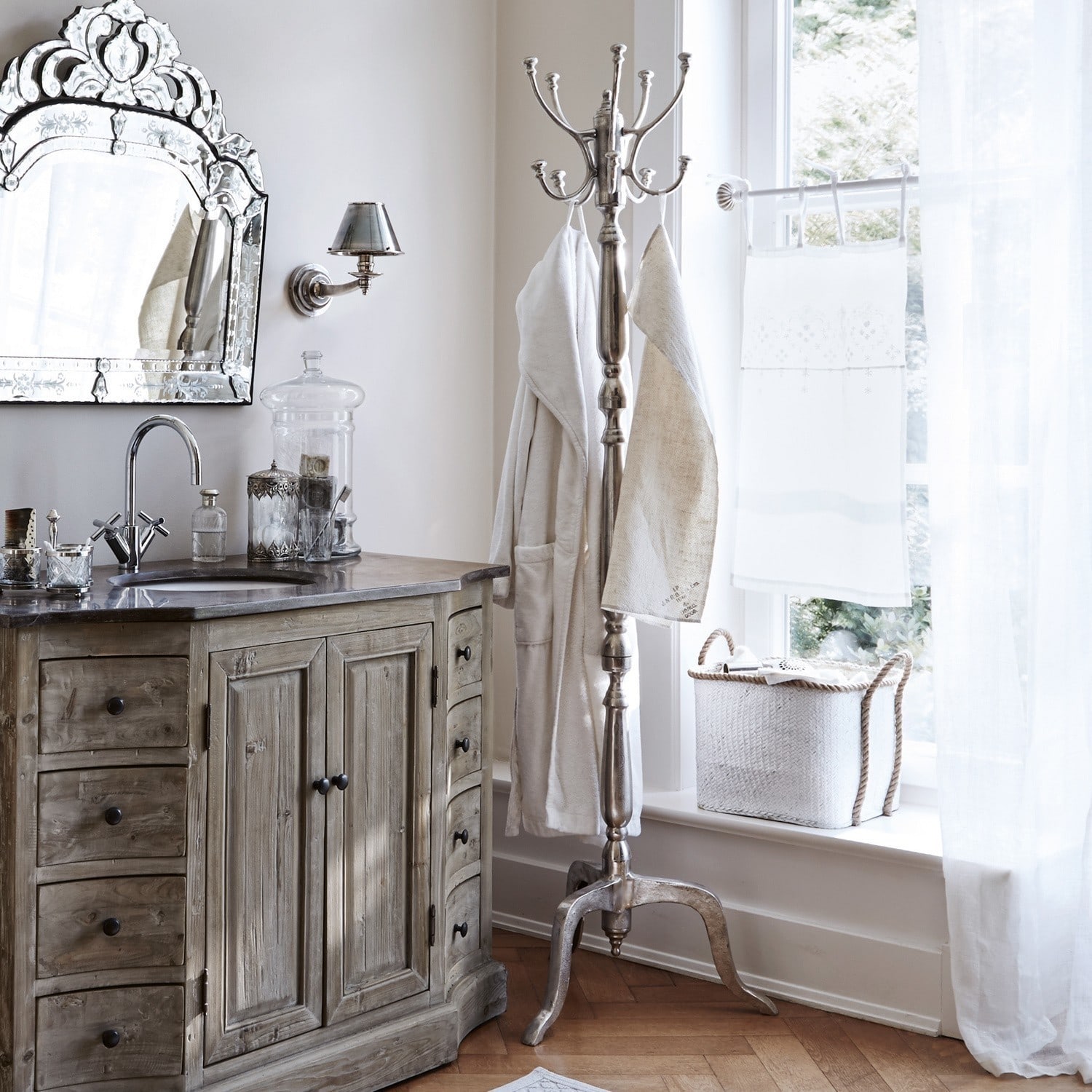 Stylowa łazienka z drewnianą szafką, metalowym wieszakiem i dekoracyjnym lustrem w jasnych kolorach