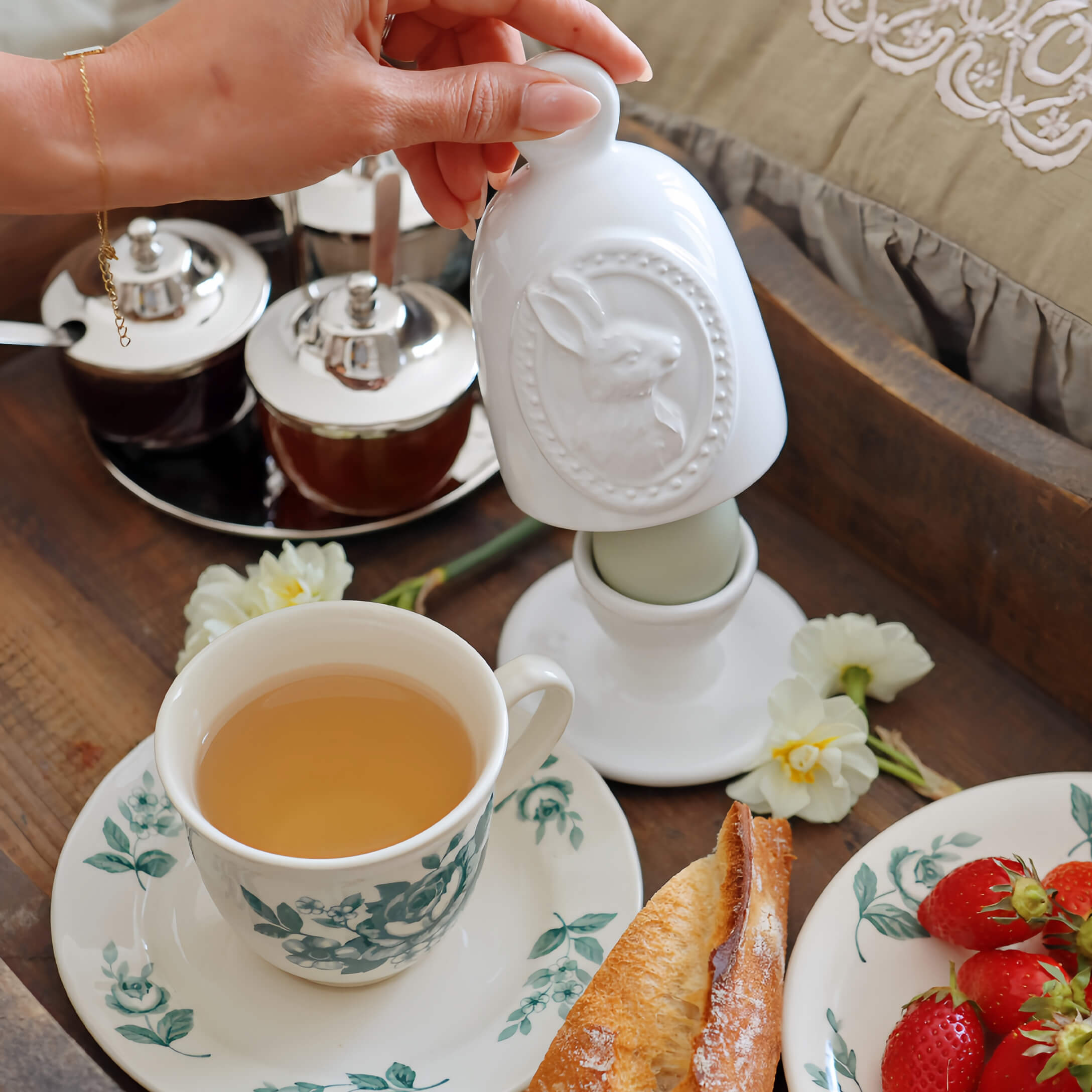 Biały ceramiczny pojemnik z motywem królika na śniadaniowym stole z herbatą i truskawkami