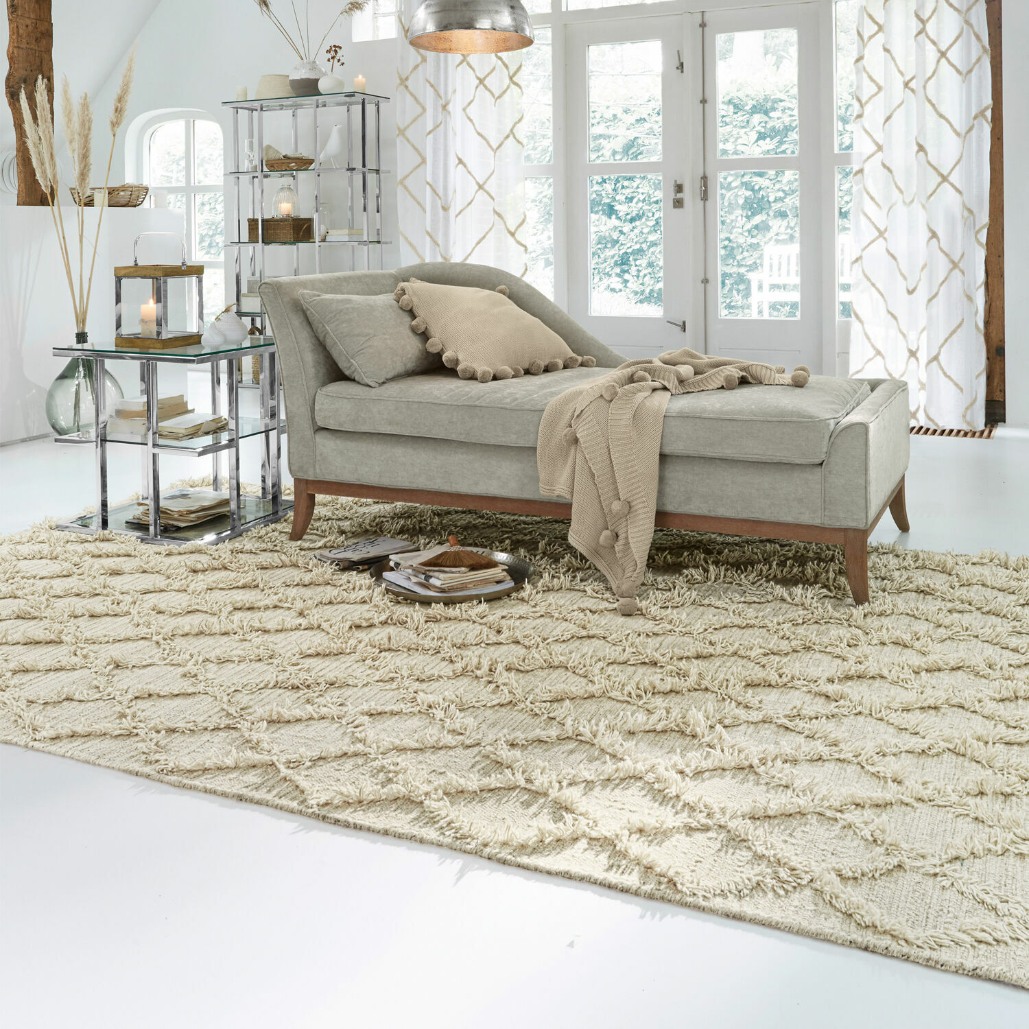 Szara tapicerowana leżanka z drewnianymi nogami na beżowym dywanie w jasnym salonie