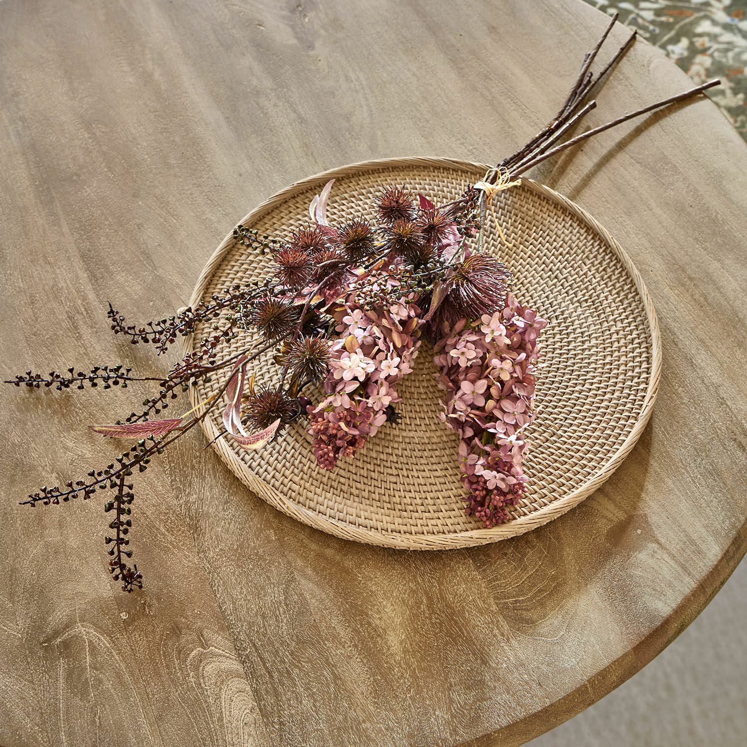 Dekoracyjny bukiet kwiatów Frinalor Dekoracyjny bukiet suszonych kwiatów w różowych i brązowych odcieniach na plecionym talerzu z rattanu