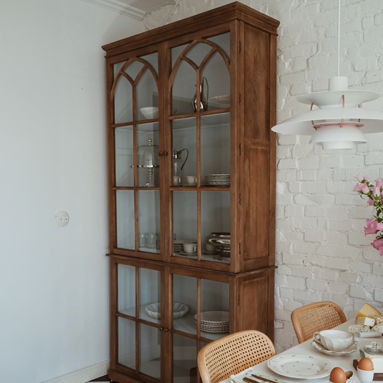 Drewniana witryna z przeszklonymi drzwiami w stylu vintage w jadalni z białą ceglaną ścianą