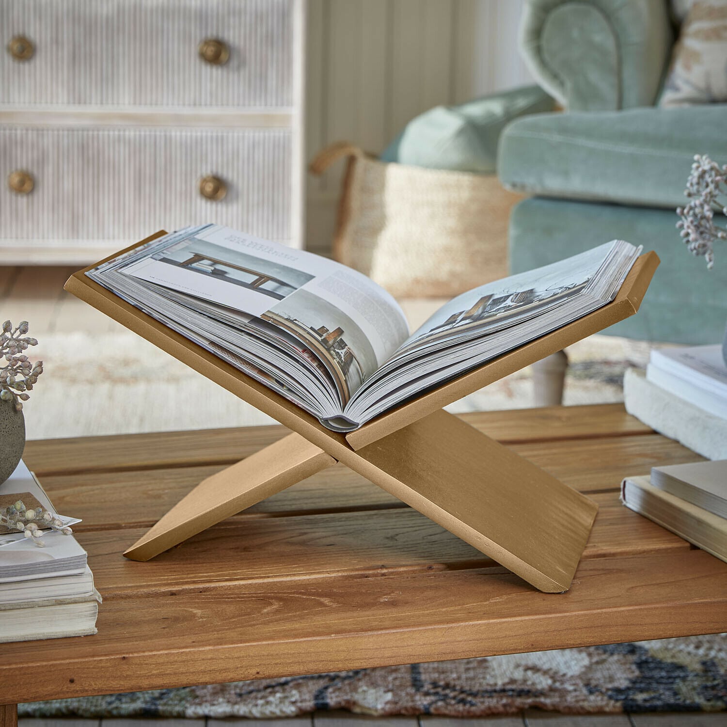 Złoty stojak na książkę z drewna na stoliku kawowym w przytulnym salonie z miękką sofą