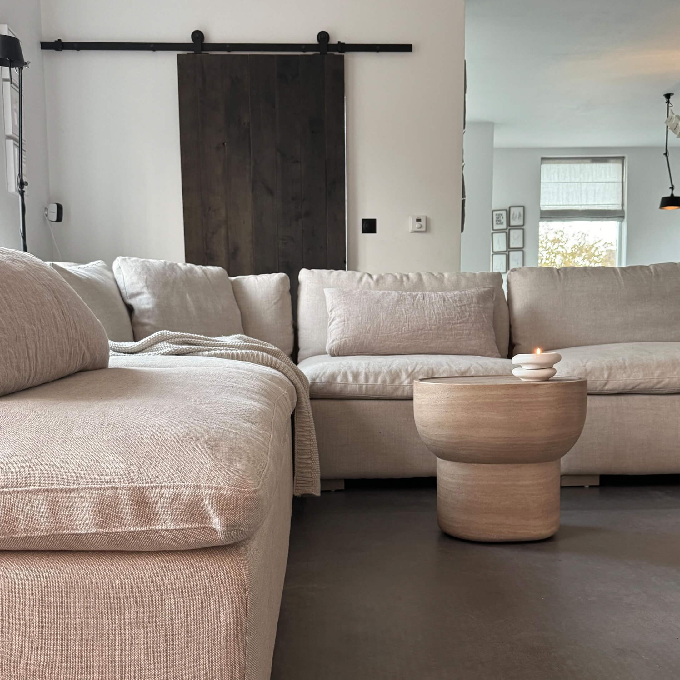 Beżowa sofa narożna z tkaniny z drewnianym stolikiem kawowym i świecą w nowoczesnym salonie