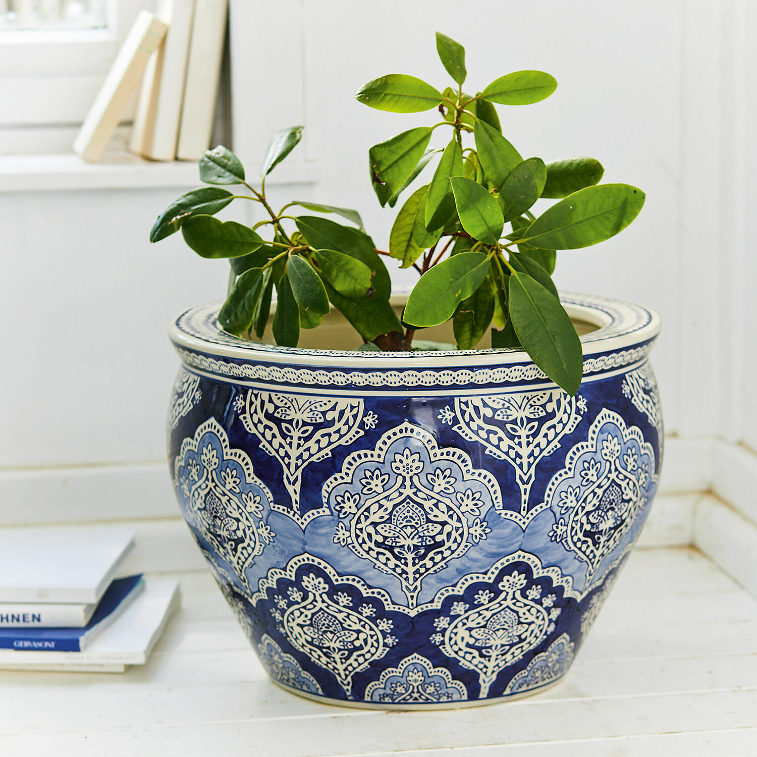 Osłonka doniczki Aurélie Ceramiczna donica w niebiesko-białe wzory z zieloną rośliną na jasnej podłodze, dekoracja wnętrza