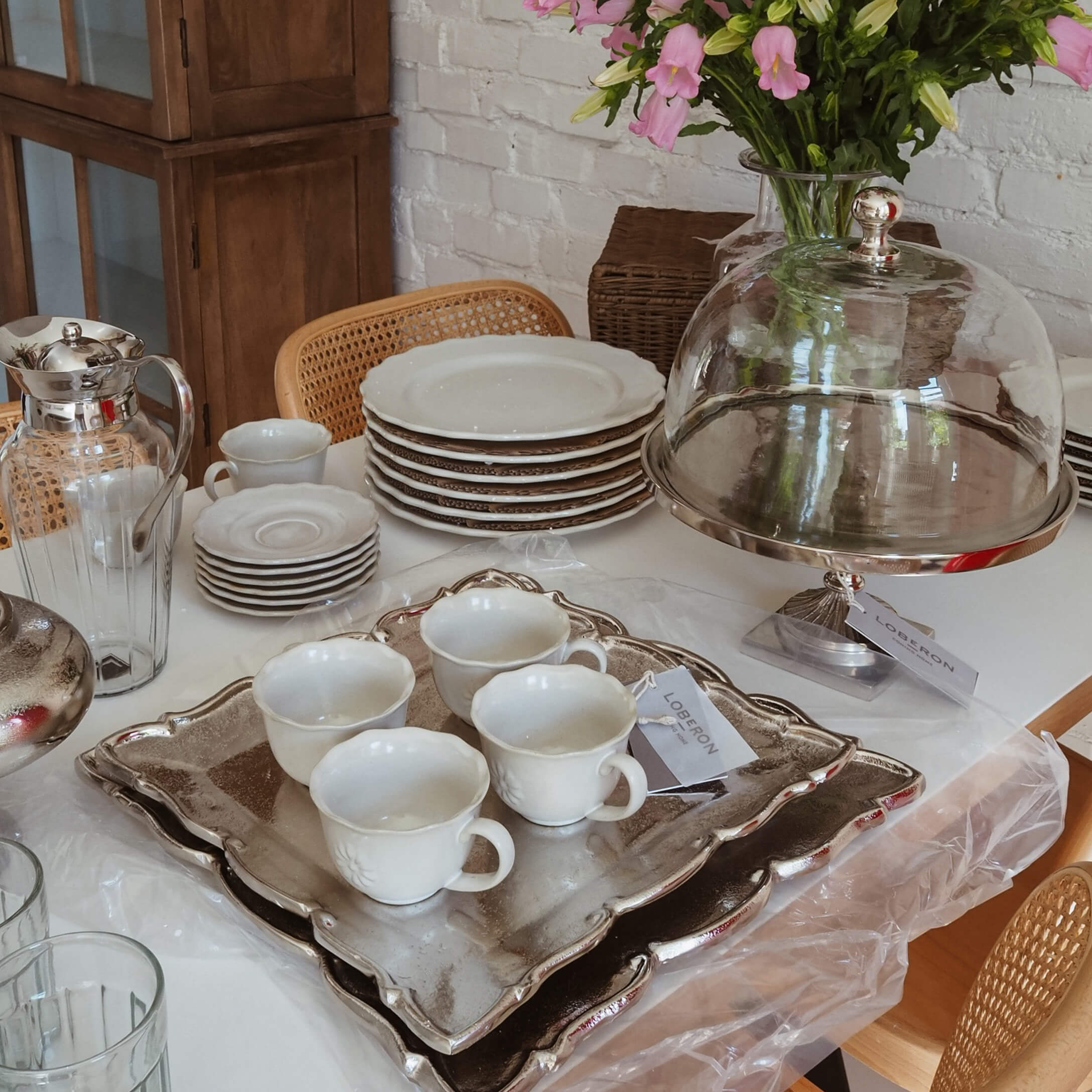 Zestaw białej porcelany z filiżankami i talerzami na srebrnej tacy, dekoracja stołu w stylu slow living