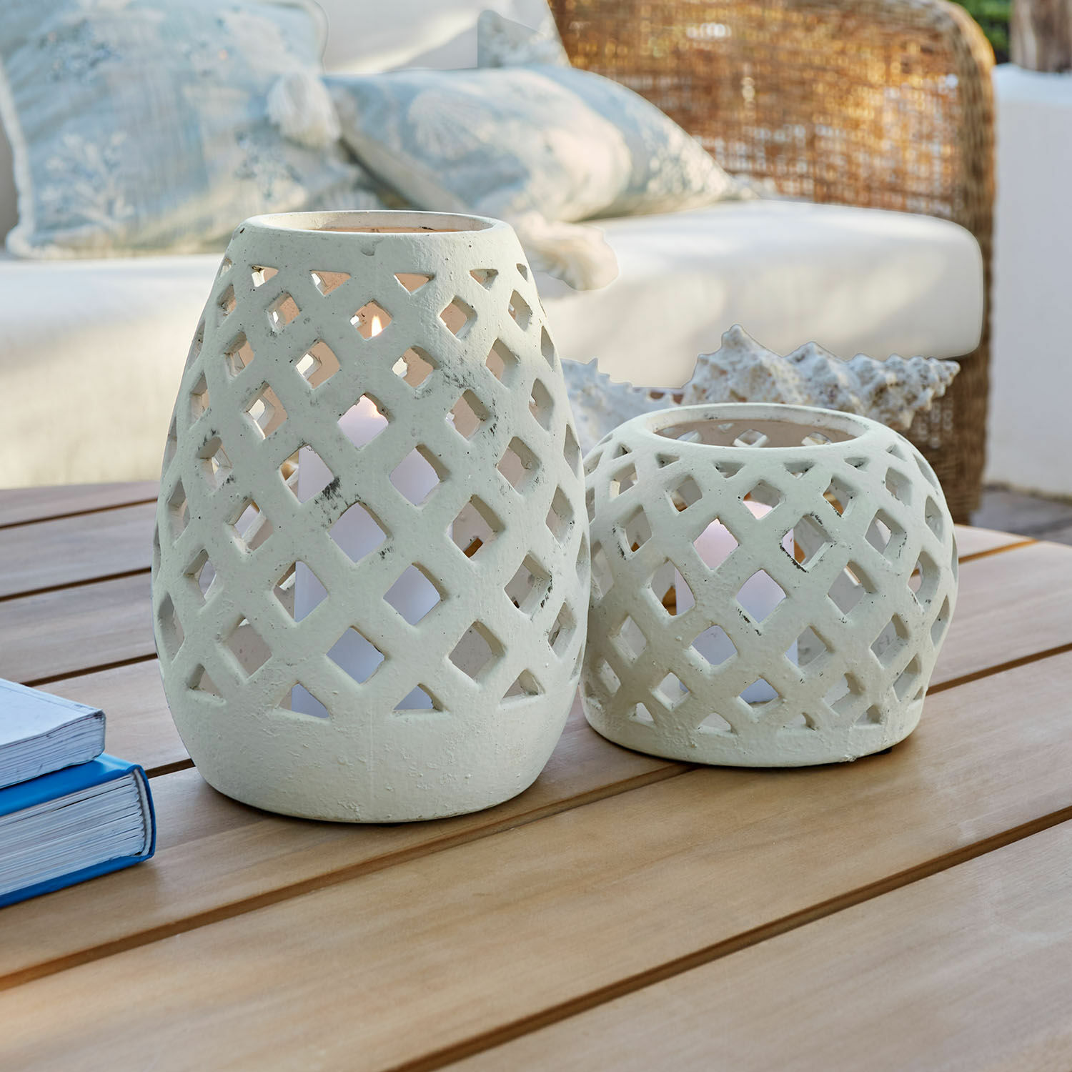 Zestaw 2 lampionów Serignac Dwa białe ceramiczne lampiony z ażurowym wzorem na drewnianym stole w salonie