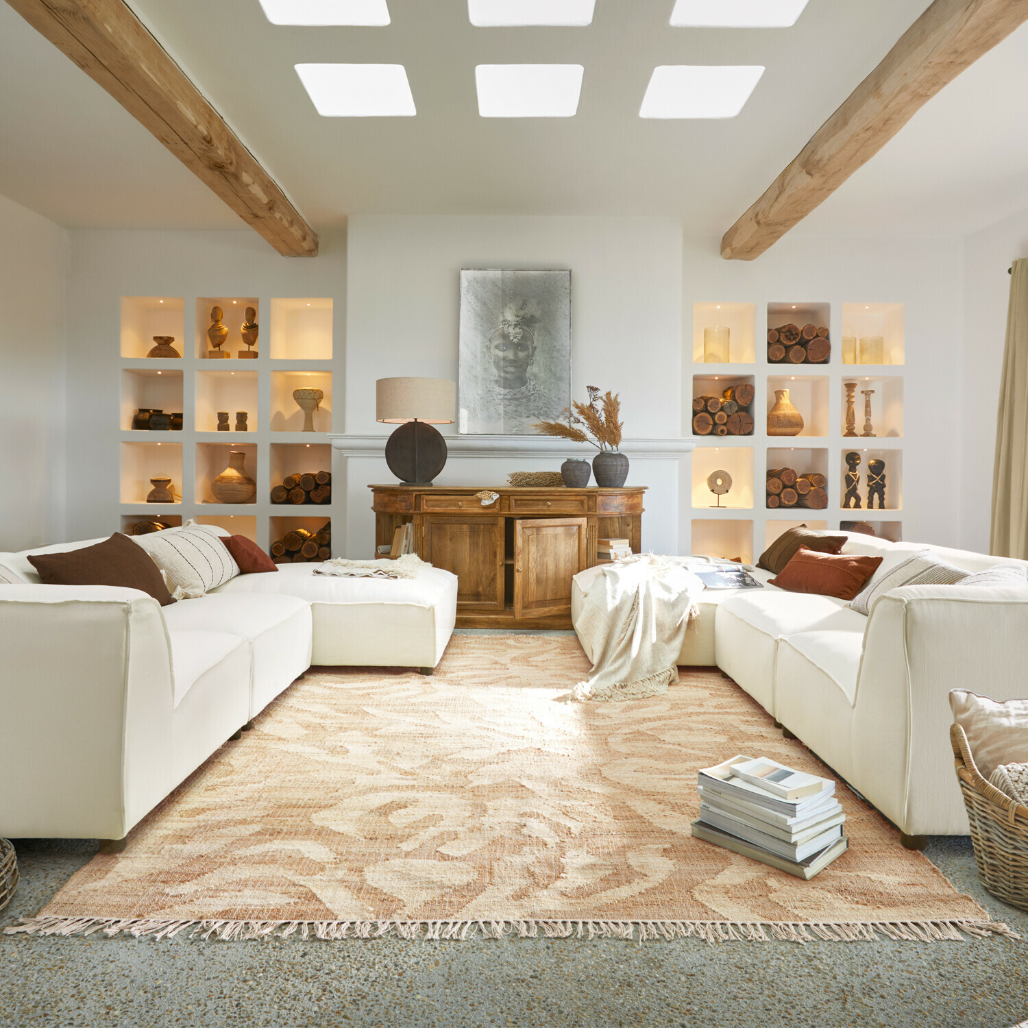 Przytulny salon z białą sofą, drewnianą komodą i beżowym dywanem o roślinnym wzorze, dekoracje z drewna