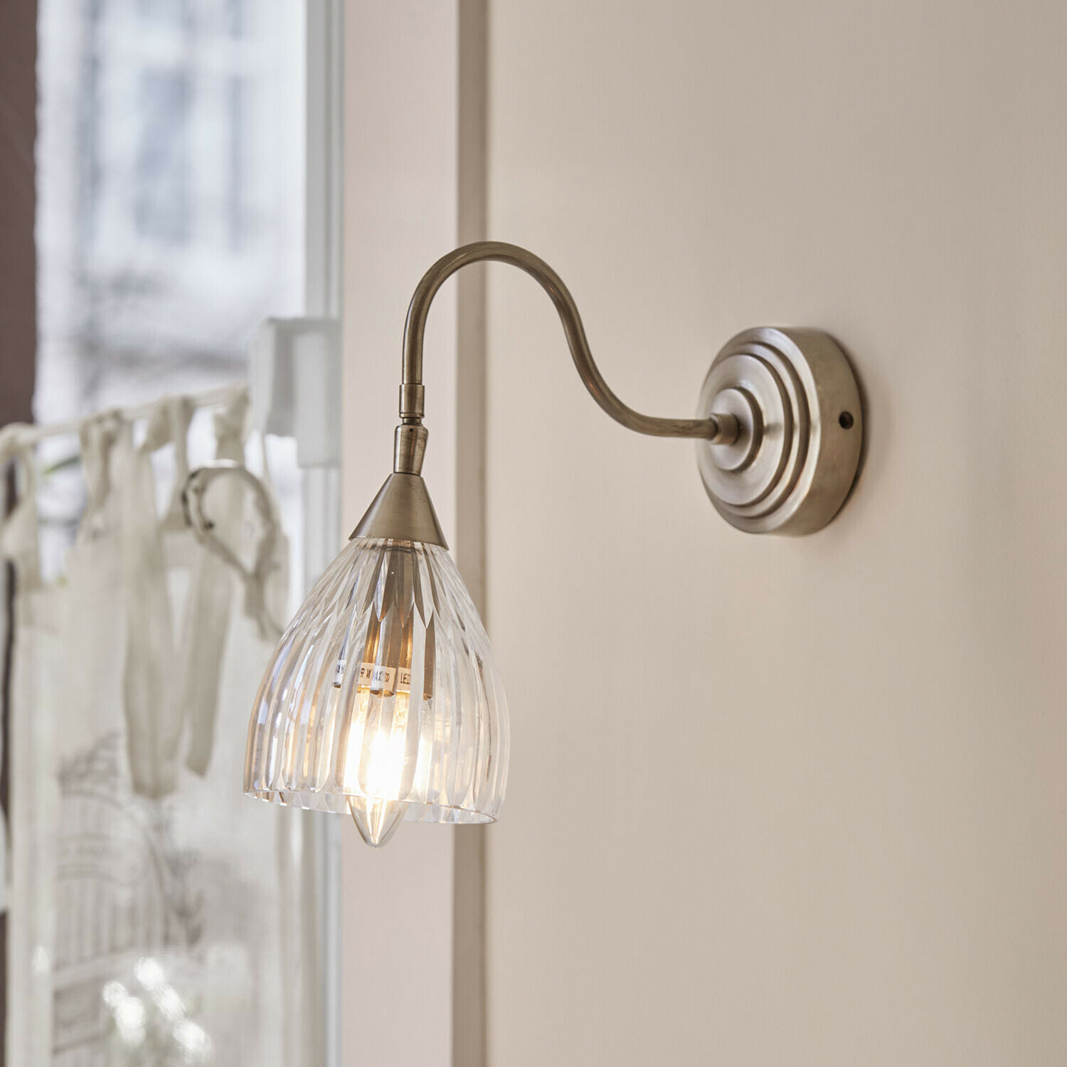 Lampa ścienna Niamhs Kinkiet ścienny z przezroczystym szklanym kloszem i metalowym ramieniem w kolorze starego srebra