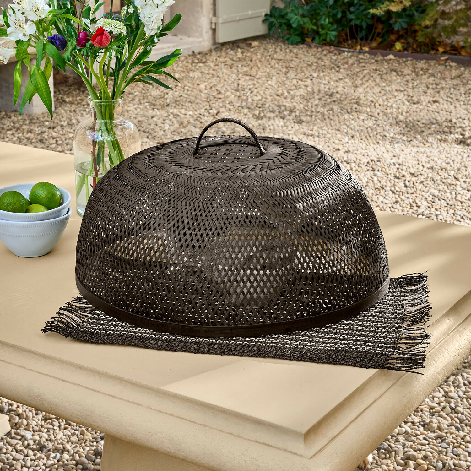 Czarna pleciona pokrywa na jedzenie z rattanu na stole ogrodowym, ochrona przed owadami