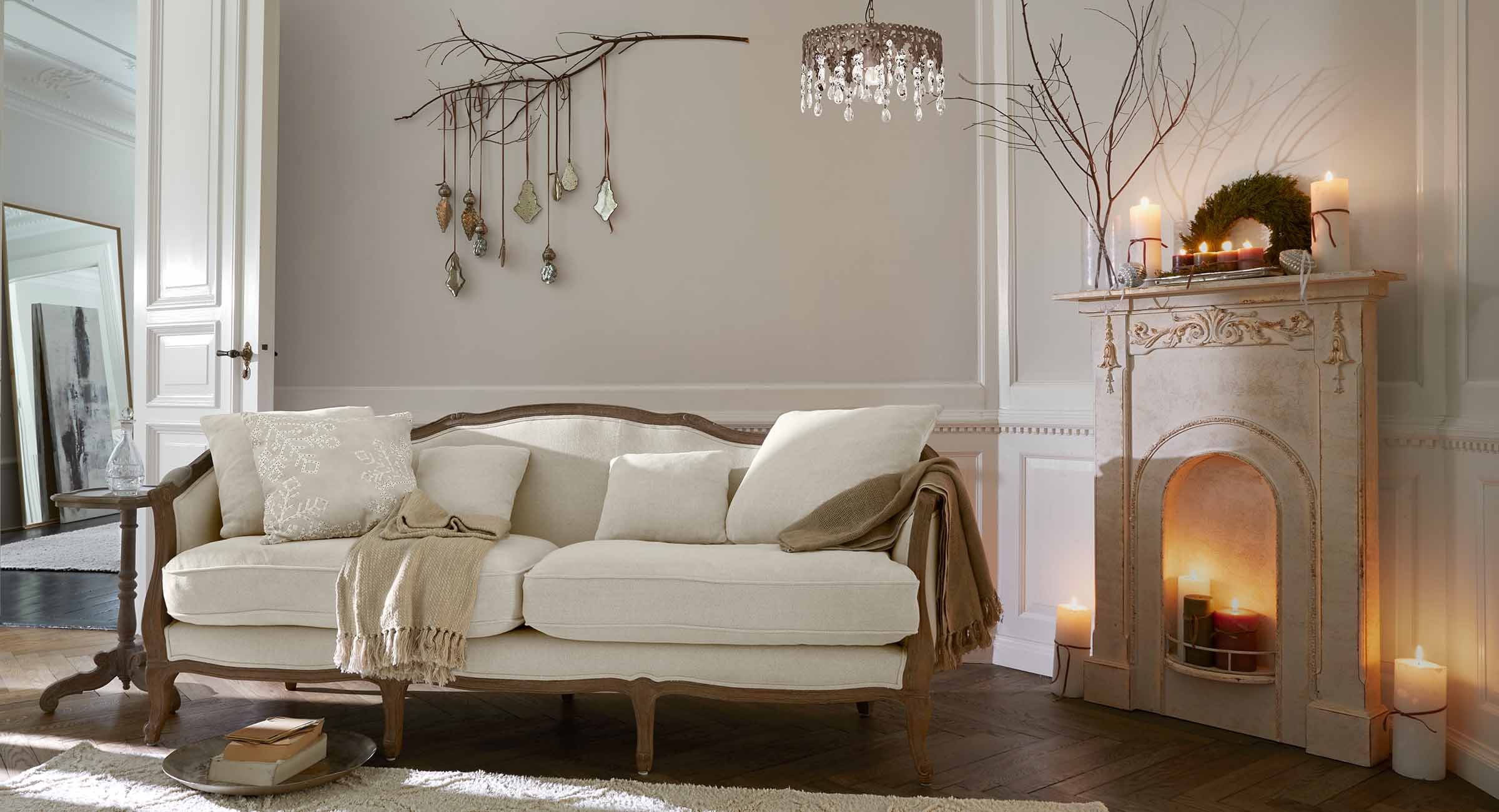 Beżowa sofa z drewnianą ramą w klasycznym salonie z kominkiem i dekoracjami ściennymi