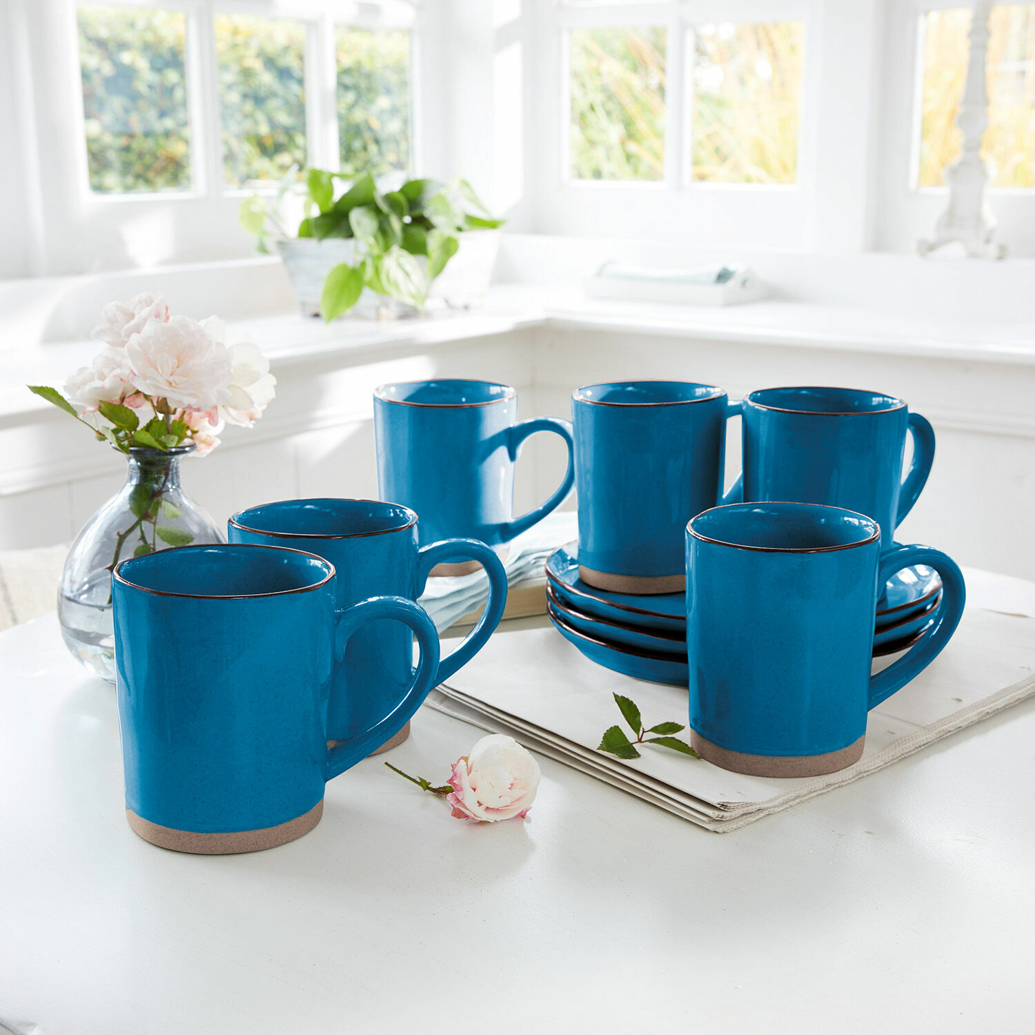 Filiżanka, zestaw 6 szt. Biarré Zestaw sześciu niebieskich ceramicznych kubków z brązowym spodem na białym stole w jasnej kuchni