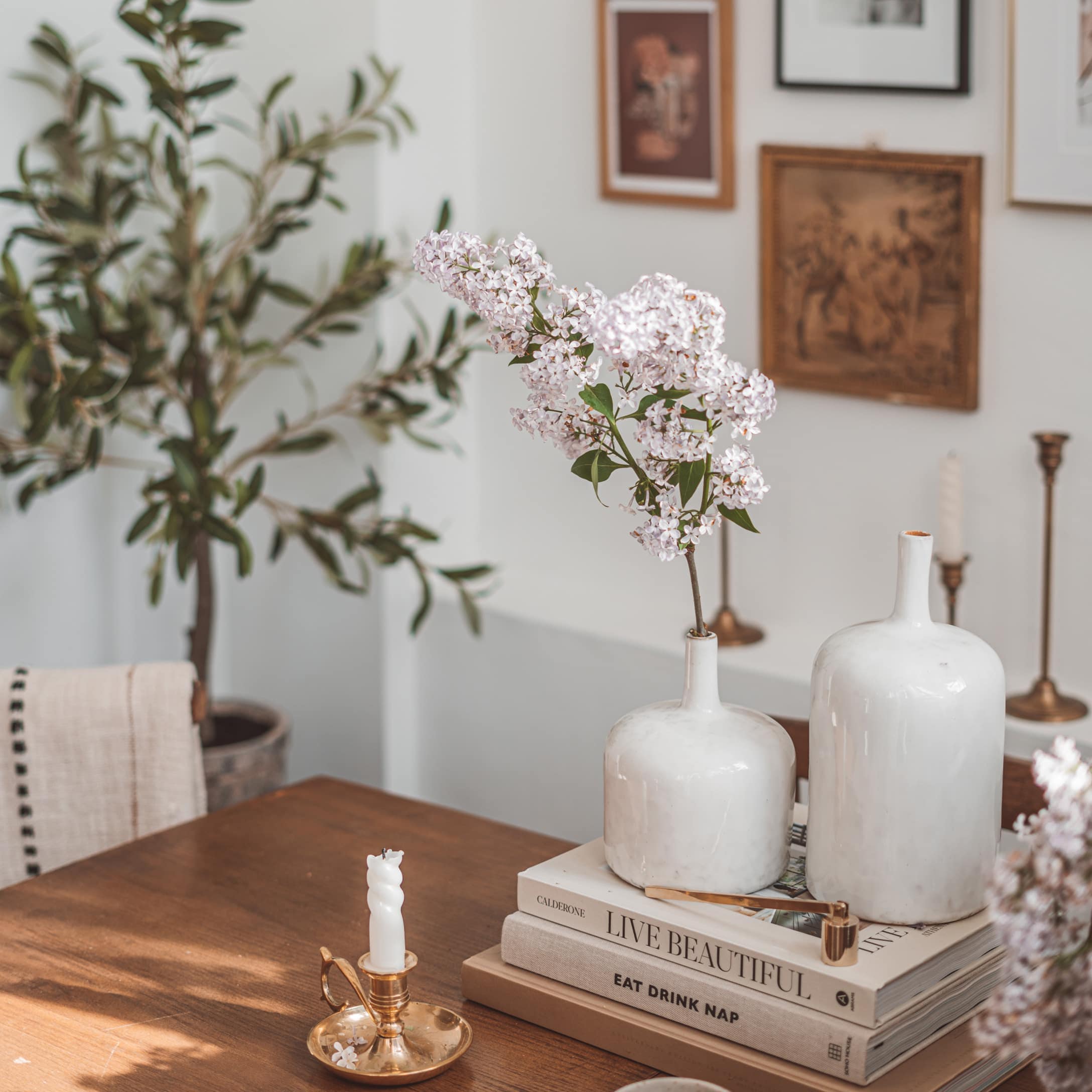 Białe ceramiczne wazony na drewnianym stole z kwiatami i złotym świecznikiem w stylu vintage