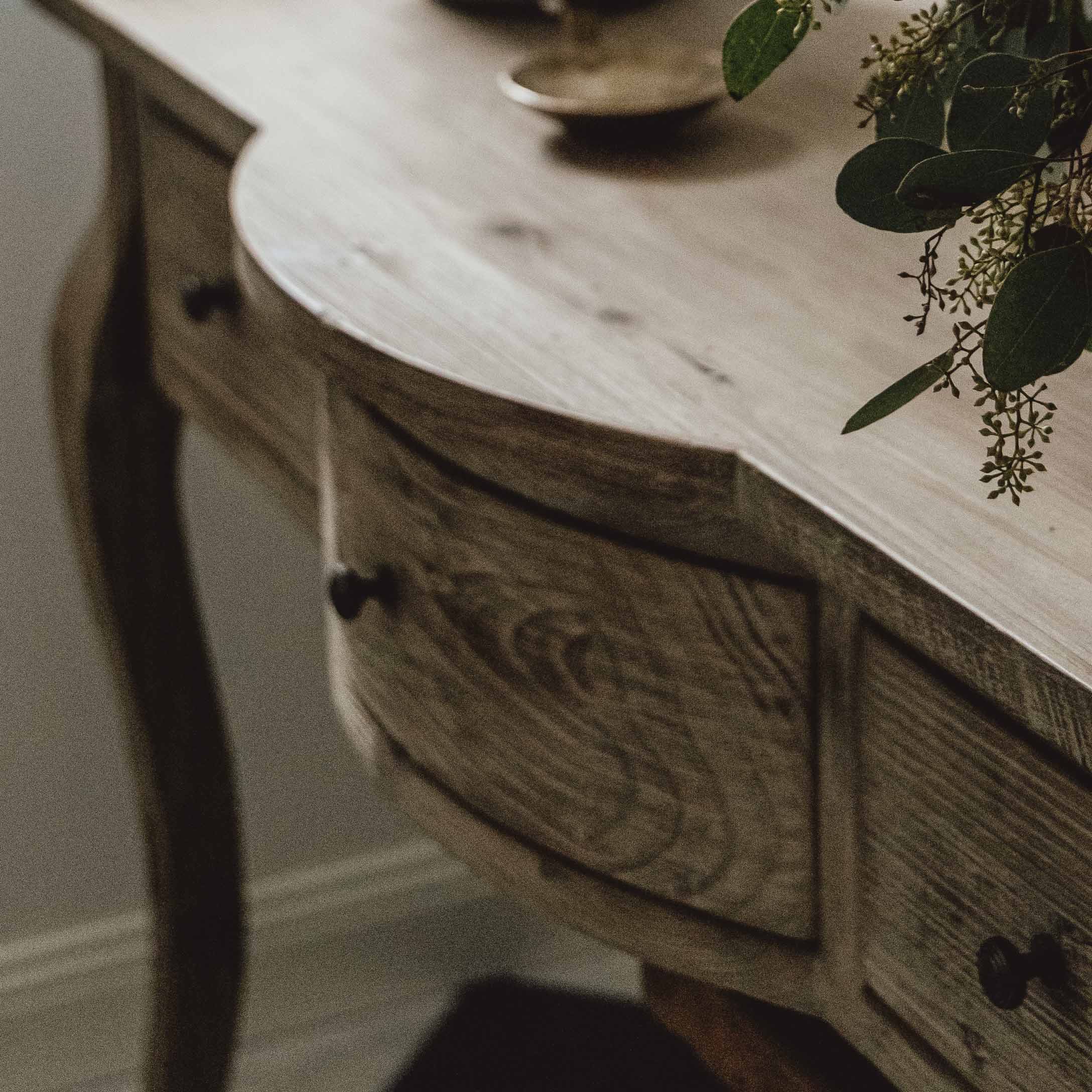 Drewniany stół z szufladami w naturalnym kolorze z dekoracją roślinną na blacie, mebel do salonu