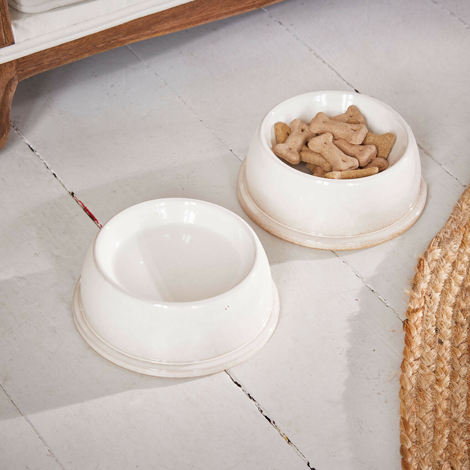 Miska na karmę, zestaw 2 szt. Kireva Dwa białe ceramiczne miski dla psa na podłodze, jedna z kośćmi do żucia, druga pusta