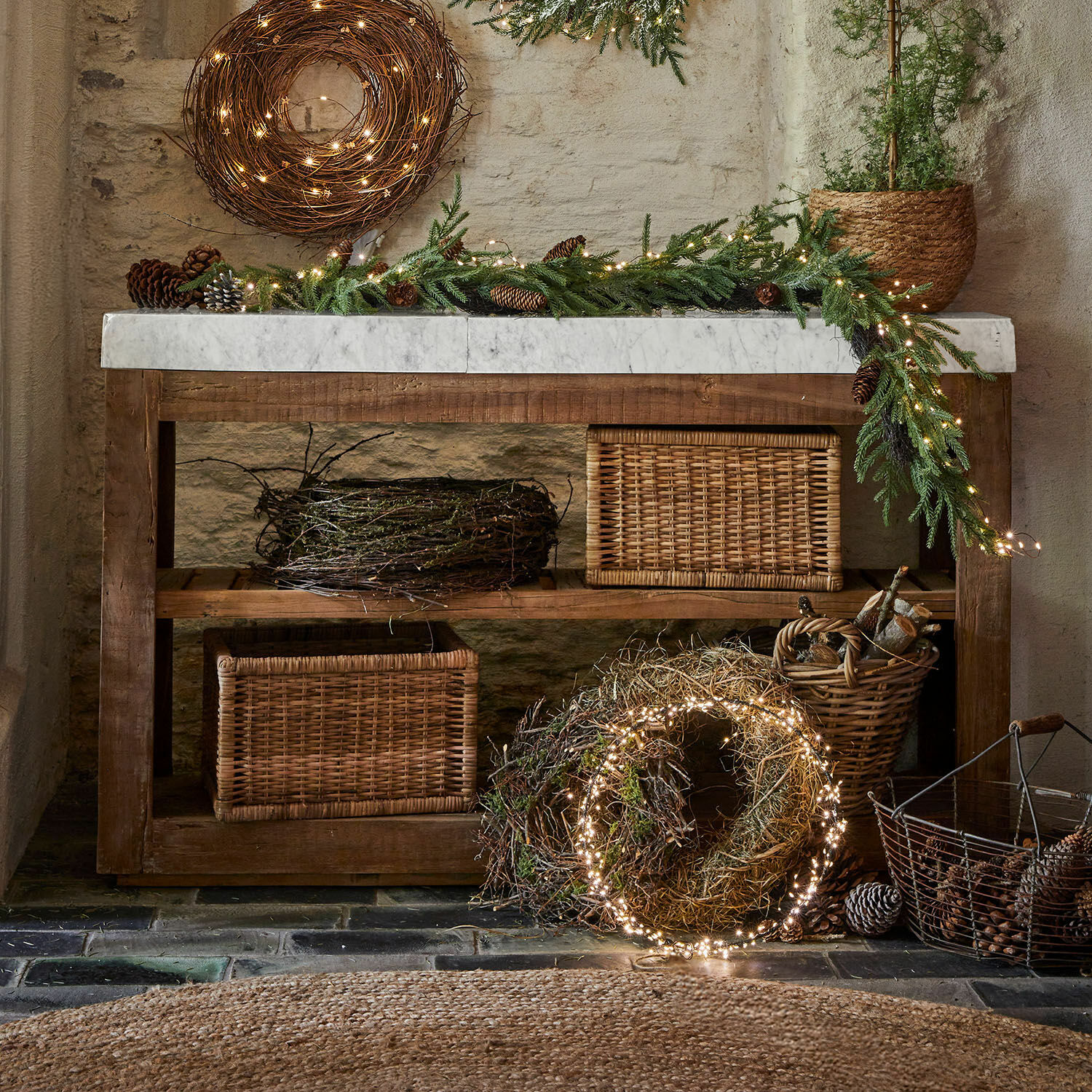 Rustykalny drewniany stolik z marmurowym blatem i dekoracjami świątecznymi z gałązek i światełek LED