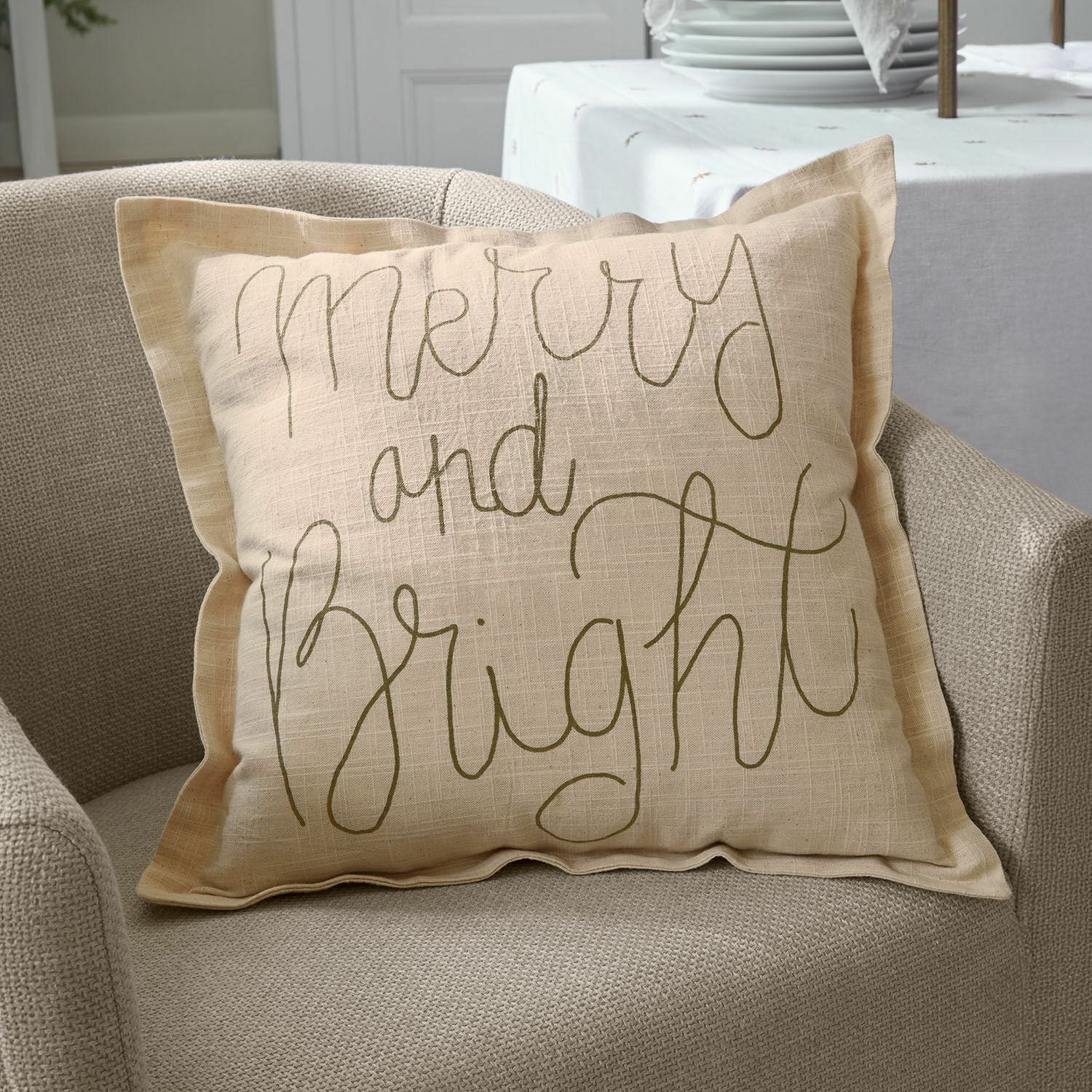 Poszewka na poduszkę Torvenna Beżowa lniana poduszka dekoracyjna z napisem Merry and Bright na beżowym fotelu, dekoracja wnętrz
